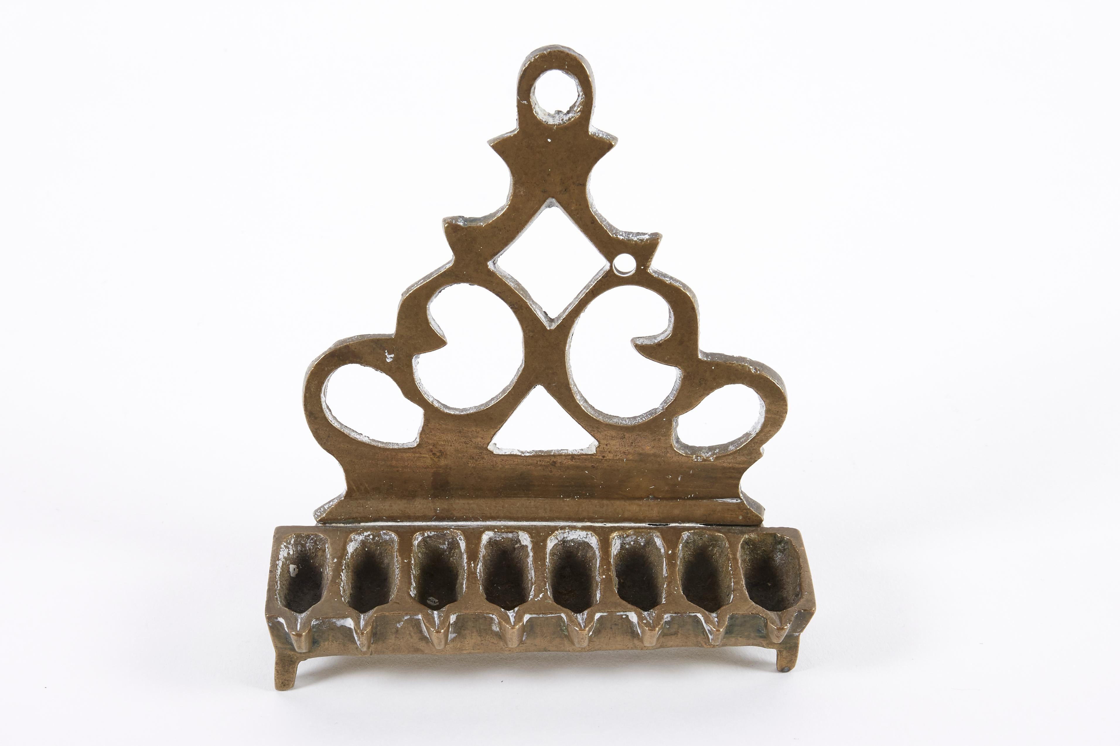 Brass Hanukkah lamp Menorah, Poland, circa 1810. 
Cast in Bench form, on four feet. The backplate is cast and pierced featuring scrollwork.
This lamp was made by the technique known as 