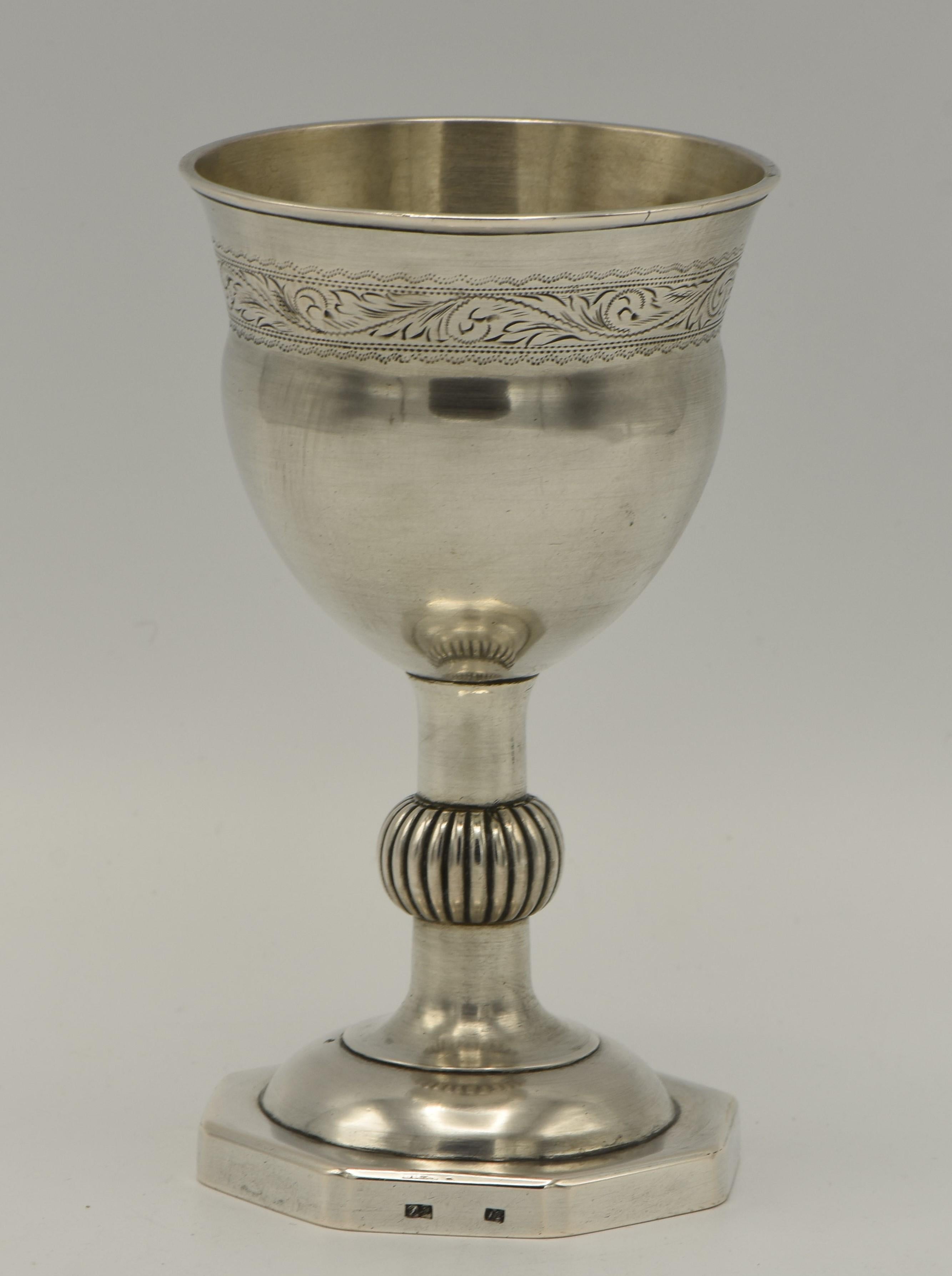 Handmade silver Kiddush goblet, Poland, circa 1820. 
Large upper portion engraved with floral decoration, set on a bulbous scroll stem on a octagonal base. Clearly struck with the quality mark 12 and maker A.G.

Kiddush cup is a ceremonial vessel to