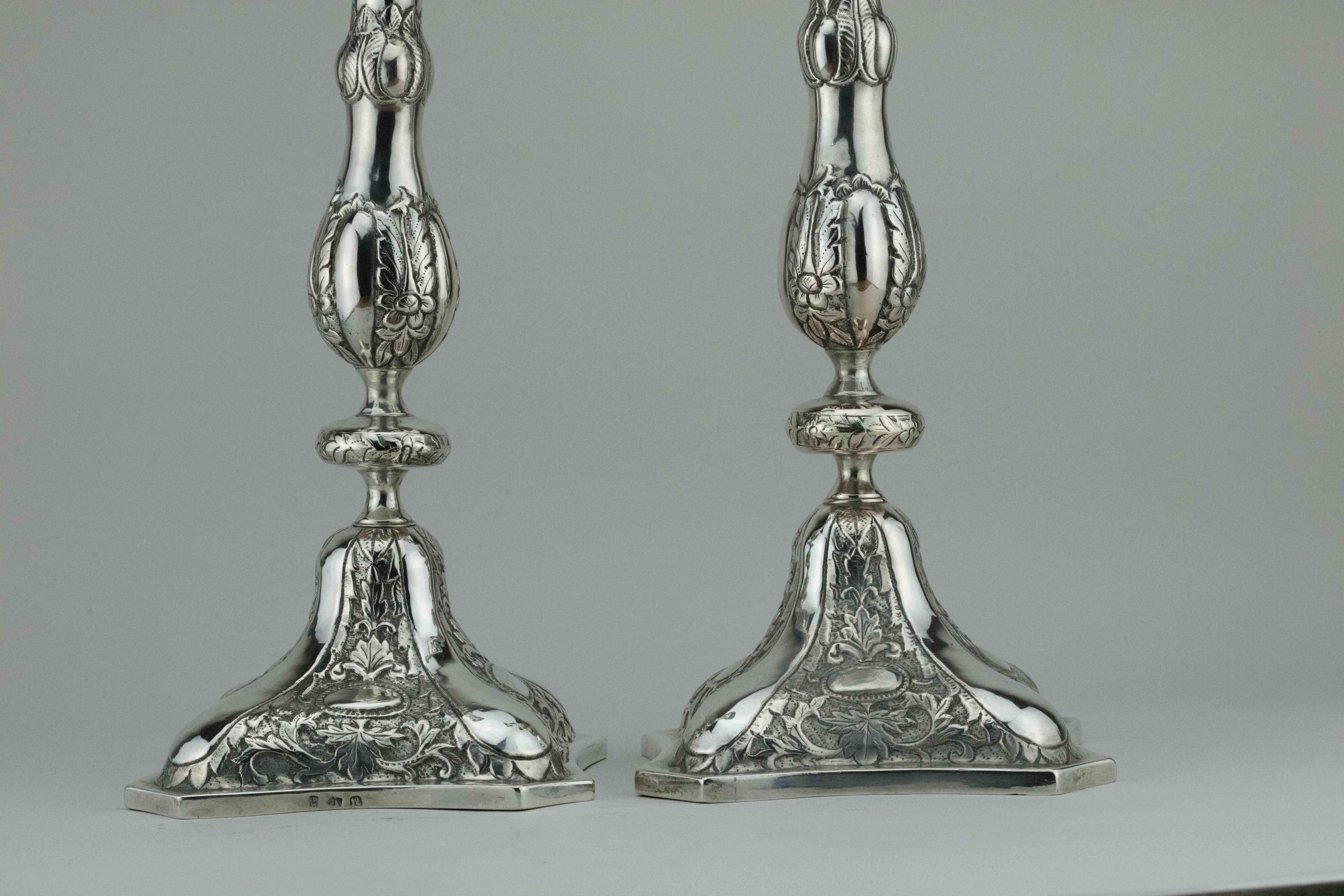 Large silver Shabbat candlesticks, Poland, circa 1880.
Beautifully chased and engraved with flowers and leaves design. 
Set on a chased stylized square base.
Marked on the base with 
