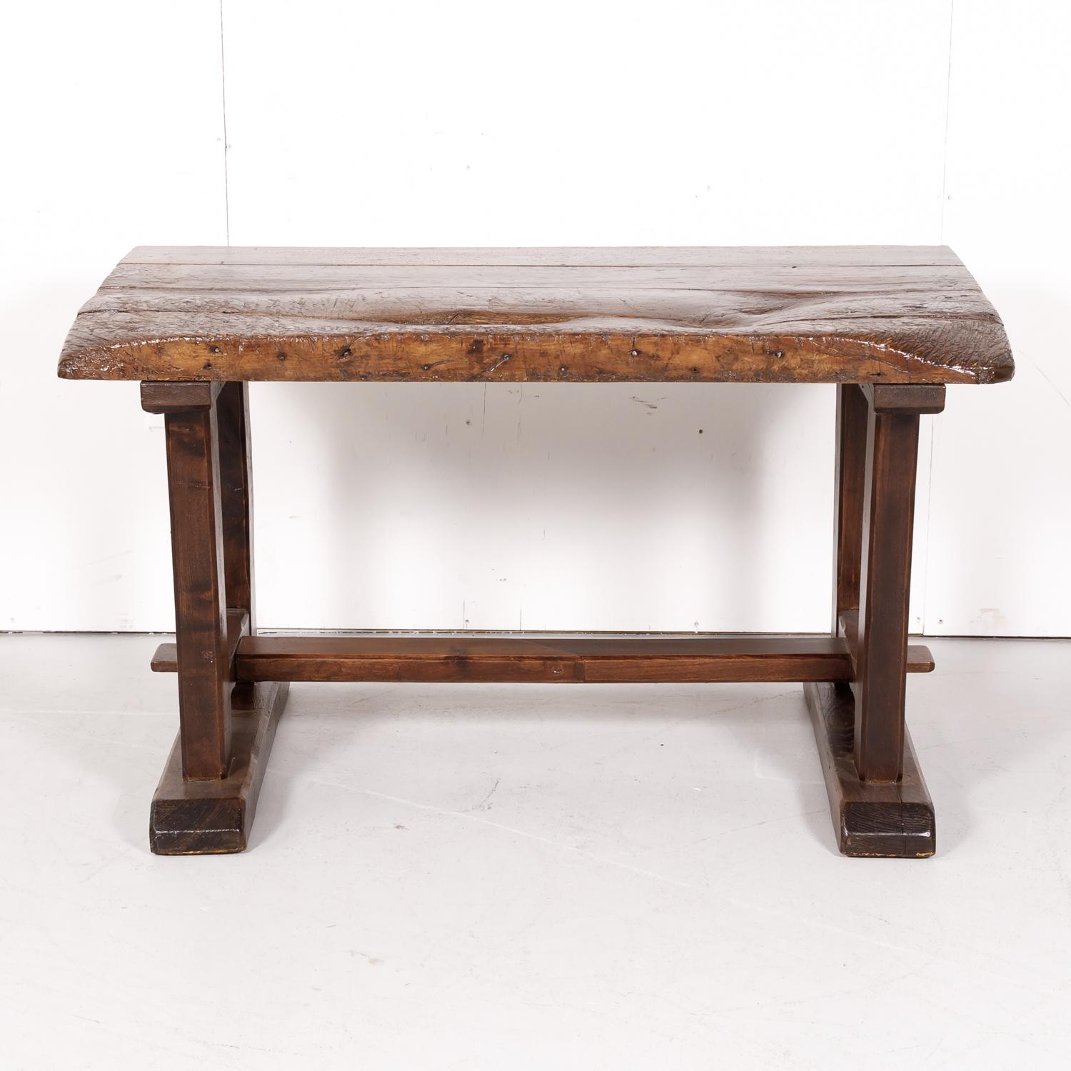 Early 19th century primitive French oak and walnut établi or side table hand constructed in Provence, having a rectangular top that is almost four inches thick supported by a trestle base joined by a centre stretcher. Whether used as a side table,