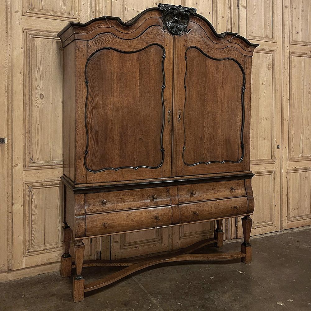 L'armoire hollandaise surélevée du début du XIXe siècle est une pièce impressionnante, conçue pour attirer l'attention dans n'importe quelle pièce tout en offrant une solution de rangement essentielle pour la famille. L'audacieuse couronne à triple