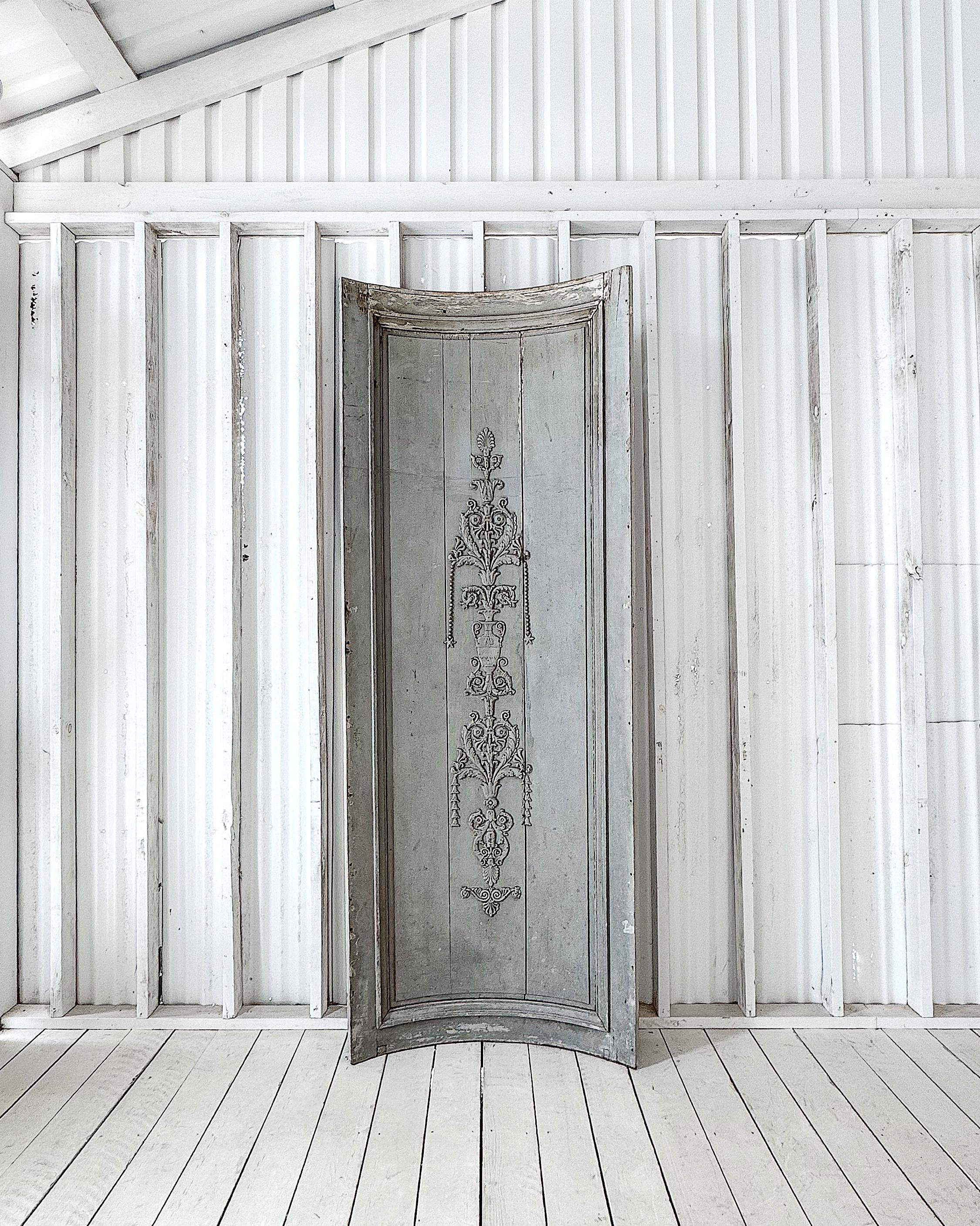 A rare and sculptural early 19th-century French boiserie panel, salvaged from a historic chateau in the countryside. Designed to fit into a curved corner, this architectural fragment retains its original pale blue paint, a quintessential hue of