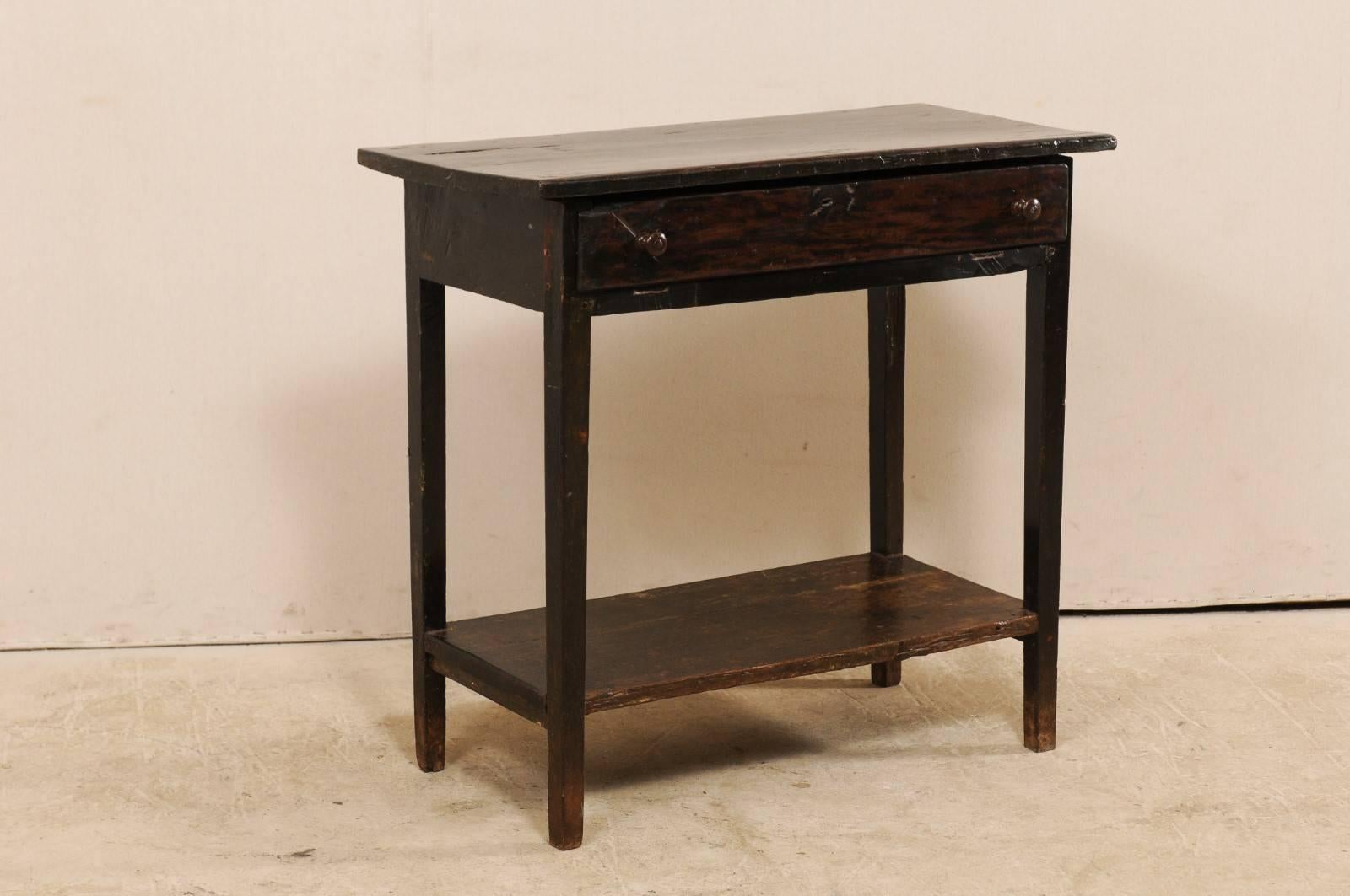 A Brazilian peroba wood side table from the early 19th century. This antique rectangular-shaped table from Brazil features a slightly overhung top above a single drawer, four squared legs with a lower bottom shelf at their centers. The table is