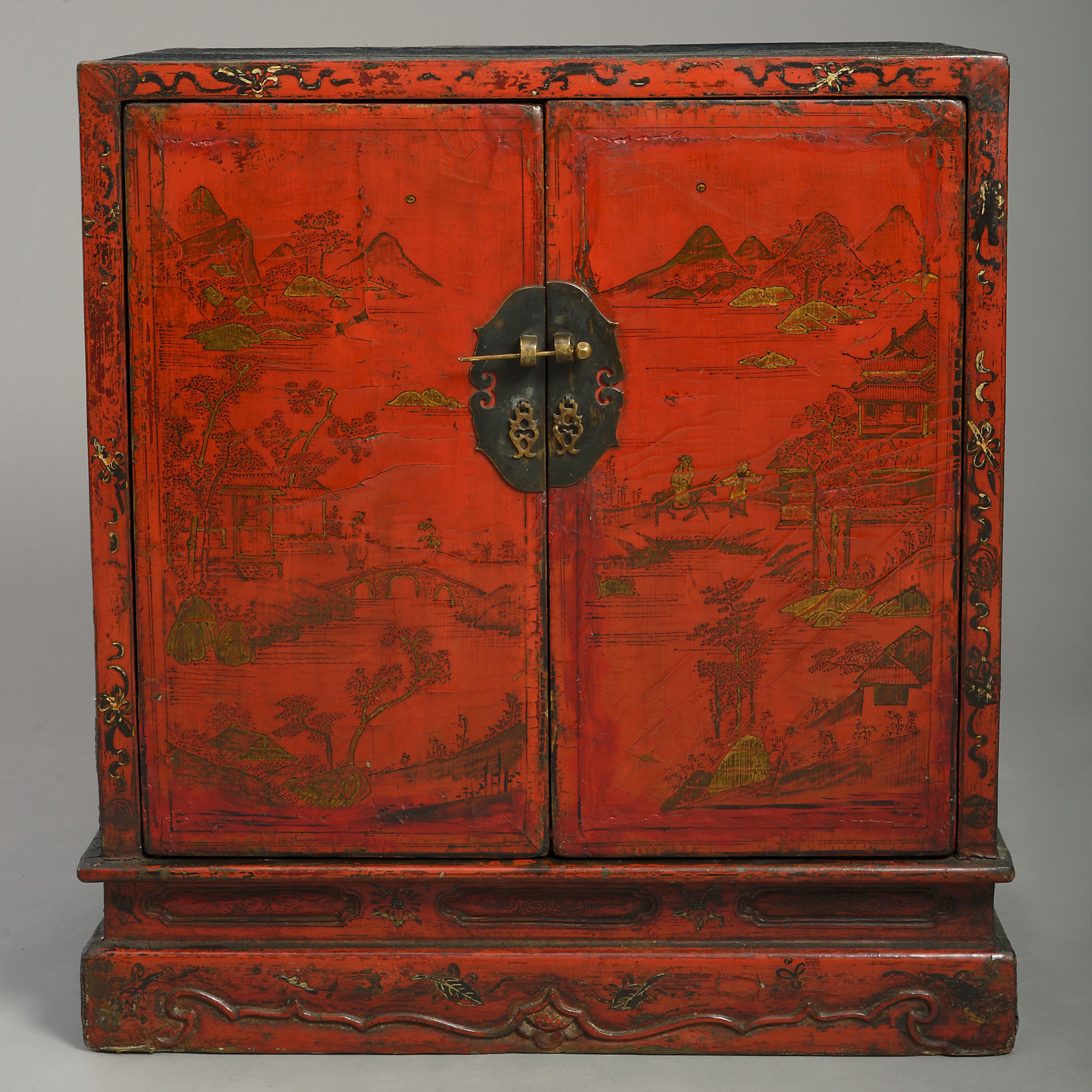 A 19th-century red lacquer cabinet, having gilded decoration throughout of figurative scenes, the two doors with brass plates opening to reveal a black painted interior with a single shelf, all raised on a carved plinth base.

  