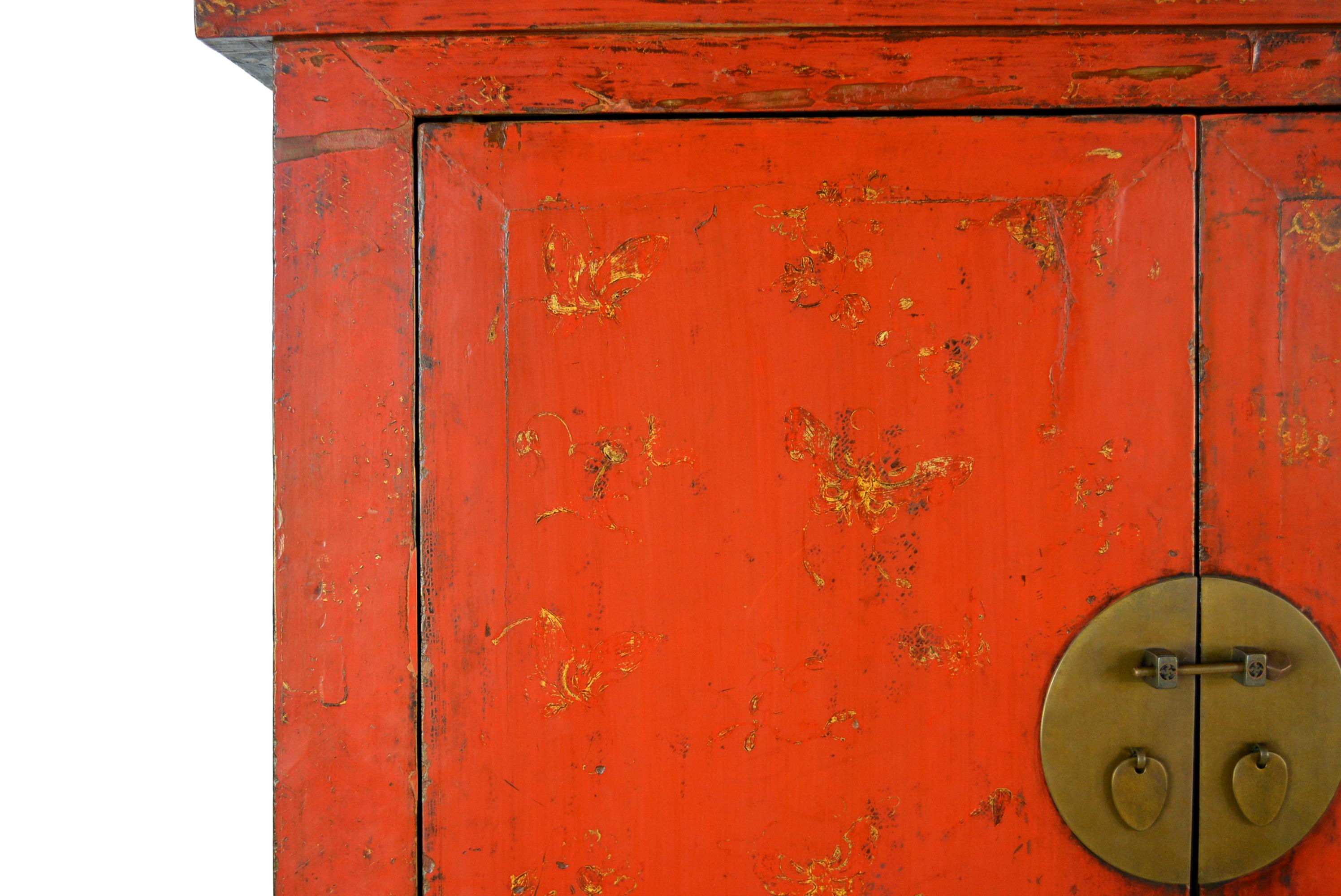 This gilt-painted red lacquer cabinet with square corners has a top board which slightly hangs over the body frame. The doors are constructed with extended pivotal hinges. The aprons are simple. The side panels are further strengthened with extra