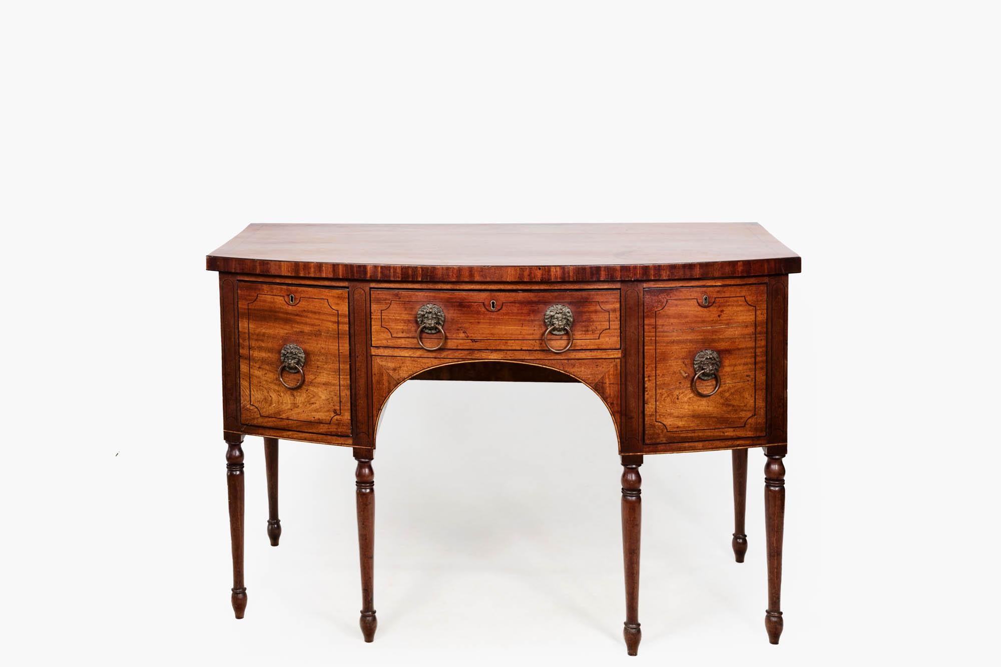 Early 19th century Regency bow-fronted mahogany side table with delicate inlay detailing. Featuring one central drawer, flanked by a cellaret drawer to the left and cupboard to the right. All three fronts have decorative fine inlaid banding and are