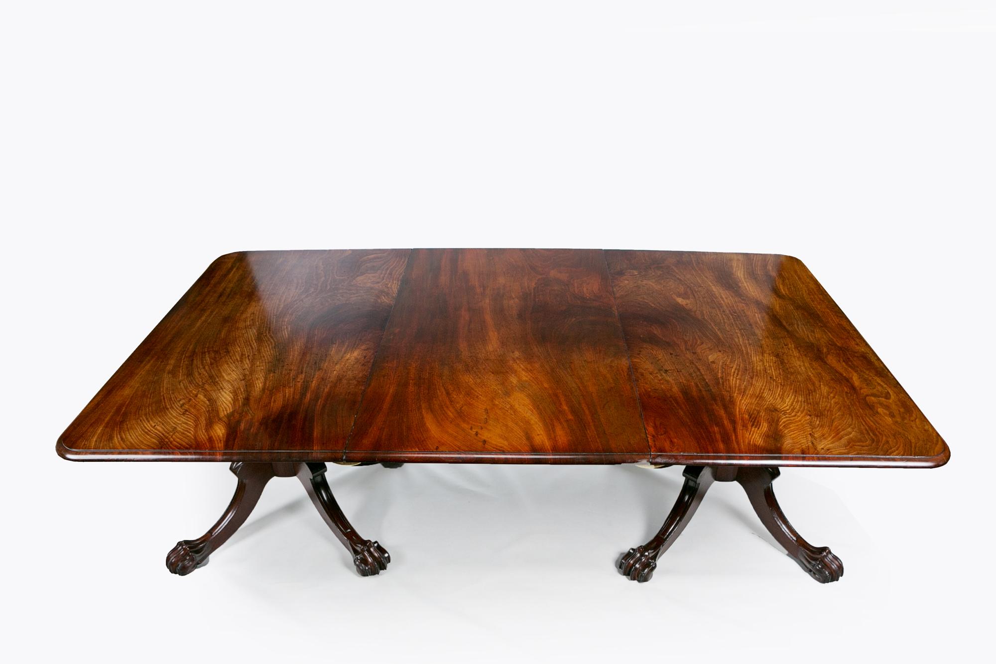 Early 19th century Regency mahogany dining table, the moulded top of rectangular form with single expanding leaf raised over two ring turned pods supported on quadripartite platform base above outswept moulded leg with foliate motif on knee