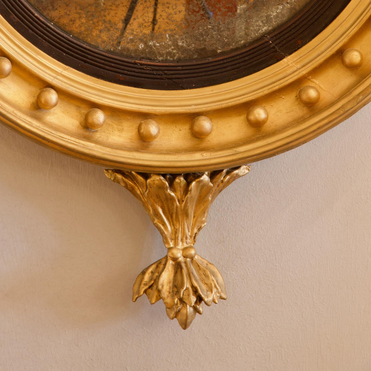 Early 19th century English Regency eagle figure round gilt and ebonized wood convex wall mirror

A large early 19th century English Regency neoclassical convex mirror in a round gilt and partially ebonized wood frame. The fluted frame is decorated