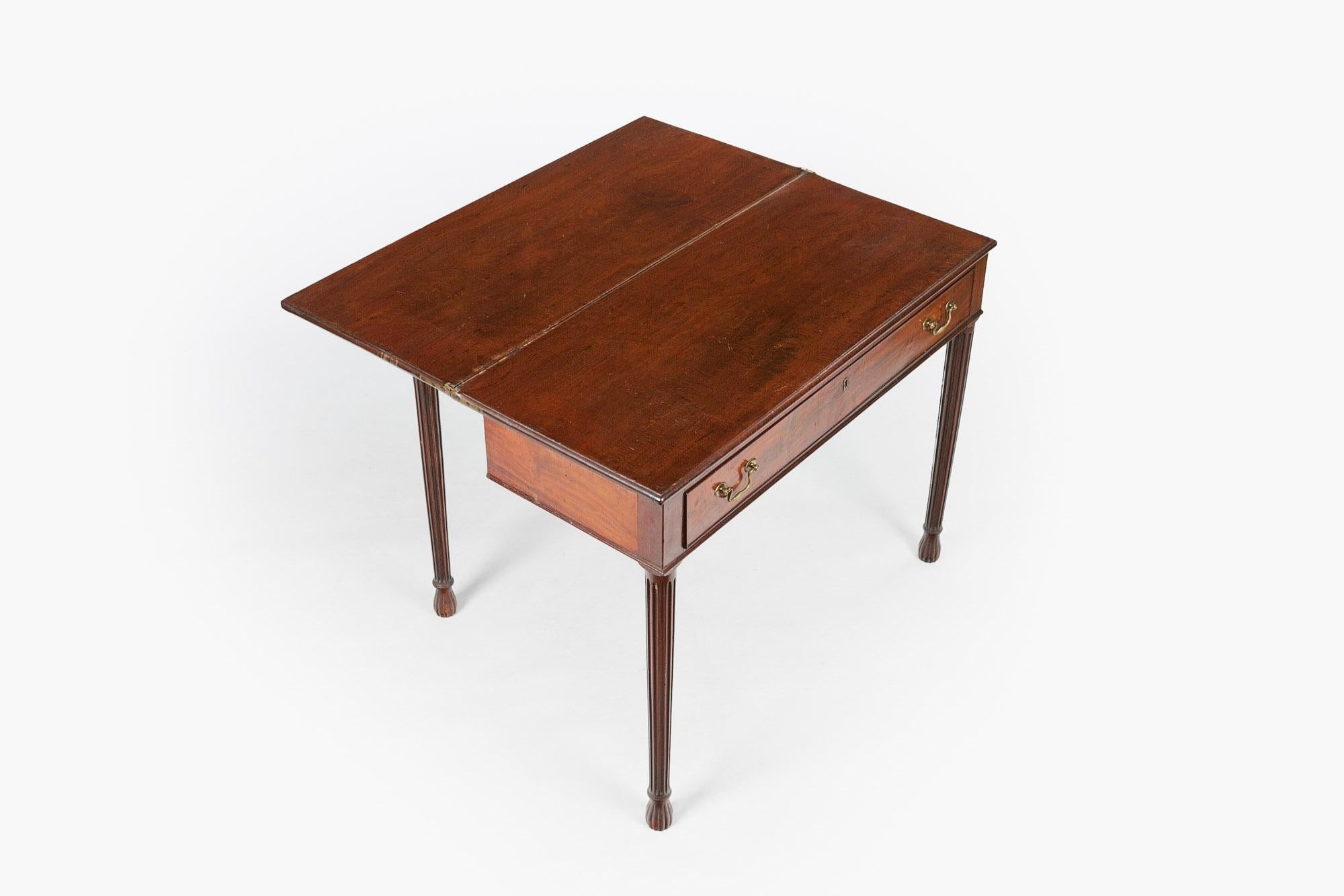 Early 19th century Regency mahogany fold over gate action table, the moulded top of square form raised over frieze with single long cockbeaded drawer and brass pulls and escutcheon supported on tapering reeded leg terminating on reeded conical foot.