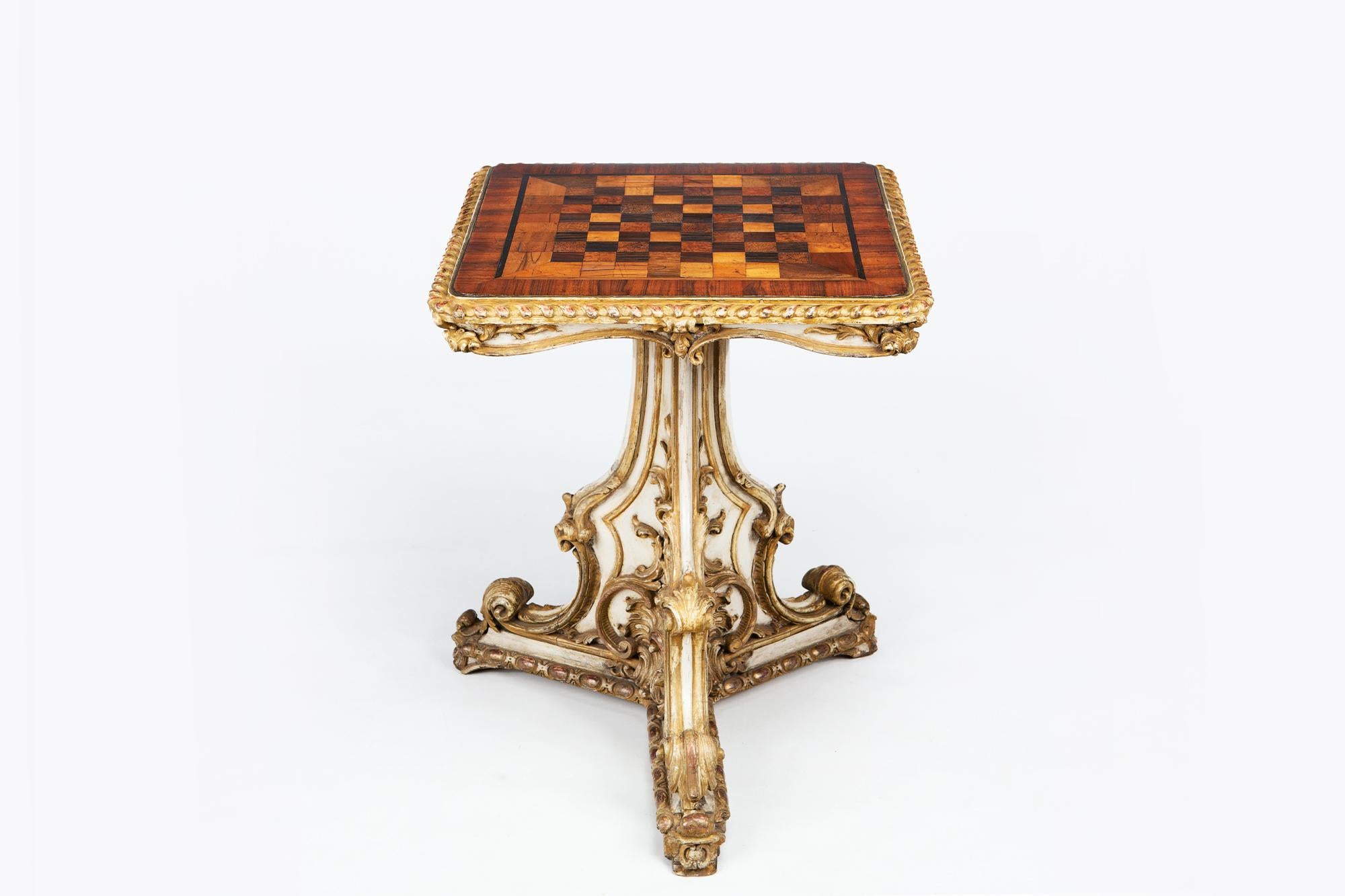 Early 19th century Regency games table, the moulded specimen top of square form with gadrooned and crossbanded rim. Inlaid ebonized line inlay and squares of satinwood, burr walnut, birds eye maple and zebrawood raised over painted and parcel gilt