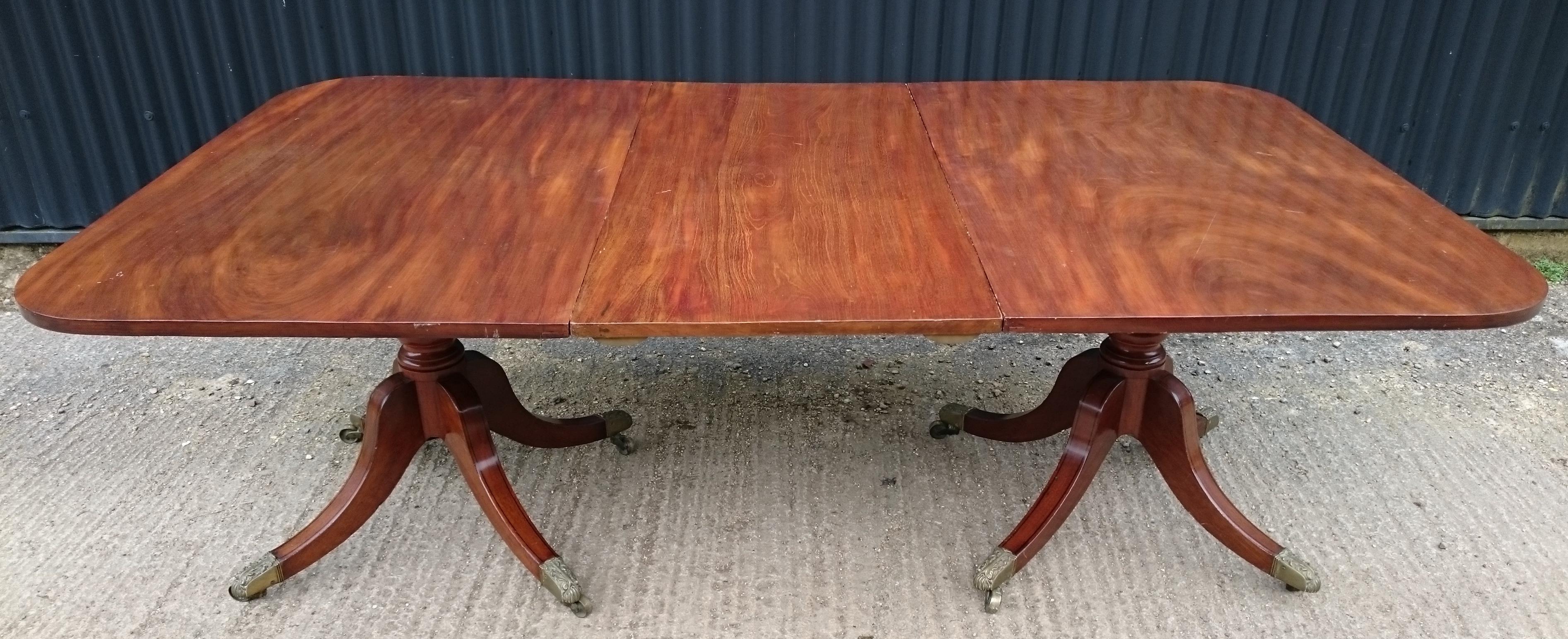 An early 19th century twin pedestal antique dining table, this is a fine Regency table standing on four splay bases which always look so much better than a three legged version. This table has an elegant leg with decorative stringing and ending in a