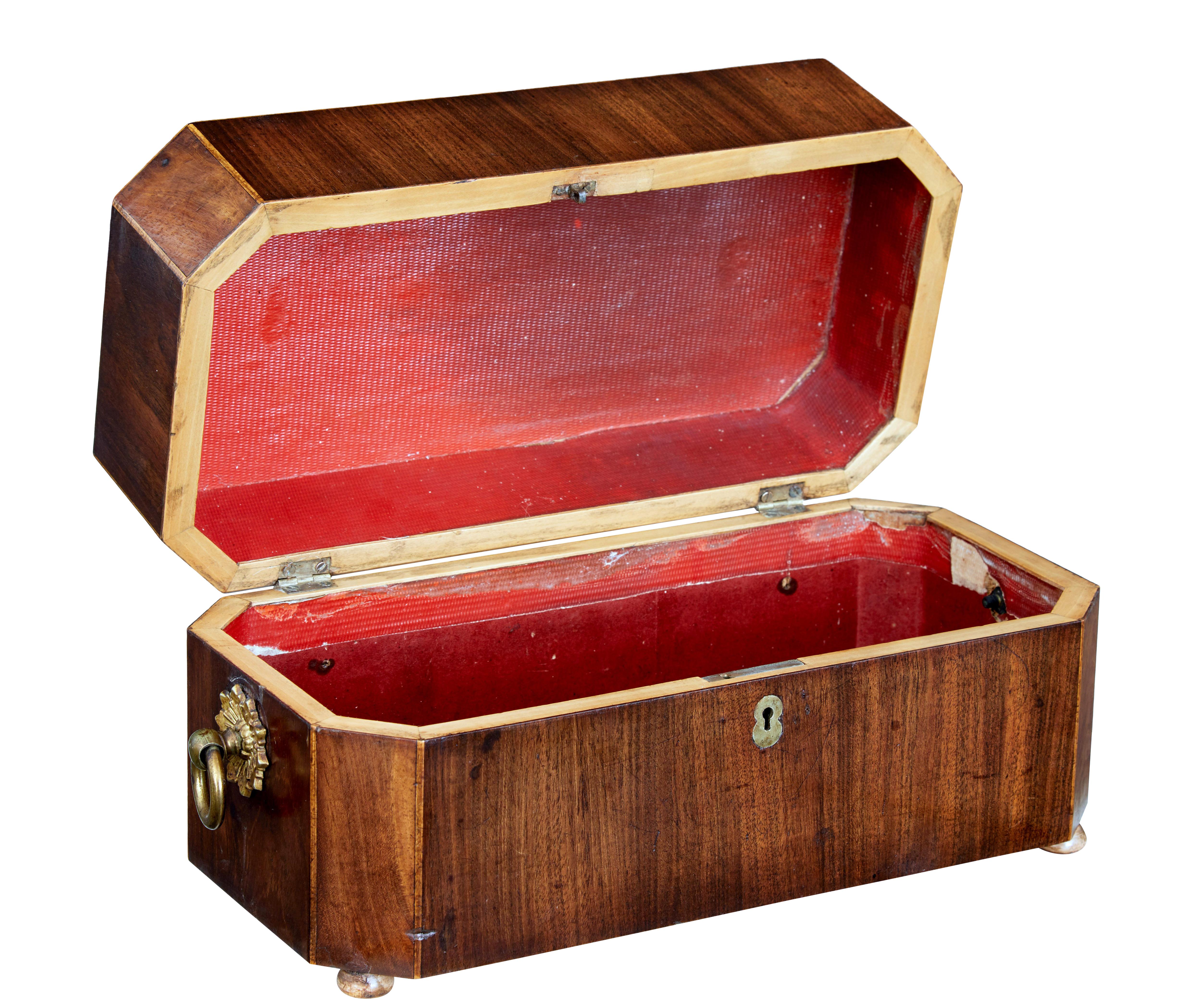 Early 19th century Regency mahogany tea caddy circa 1820.

Made using flame mahogany veneers.  Brass handles with star motif to the sides.  Canted corners strung with satinwood.  Standing on flat bun feet.

Paper lined interior with no compartments