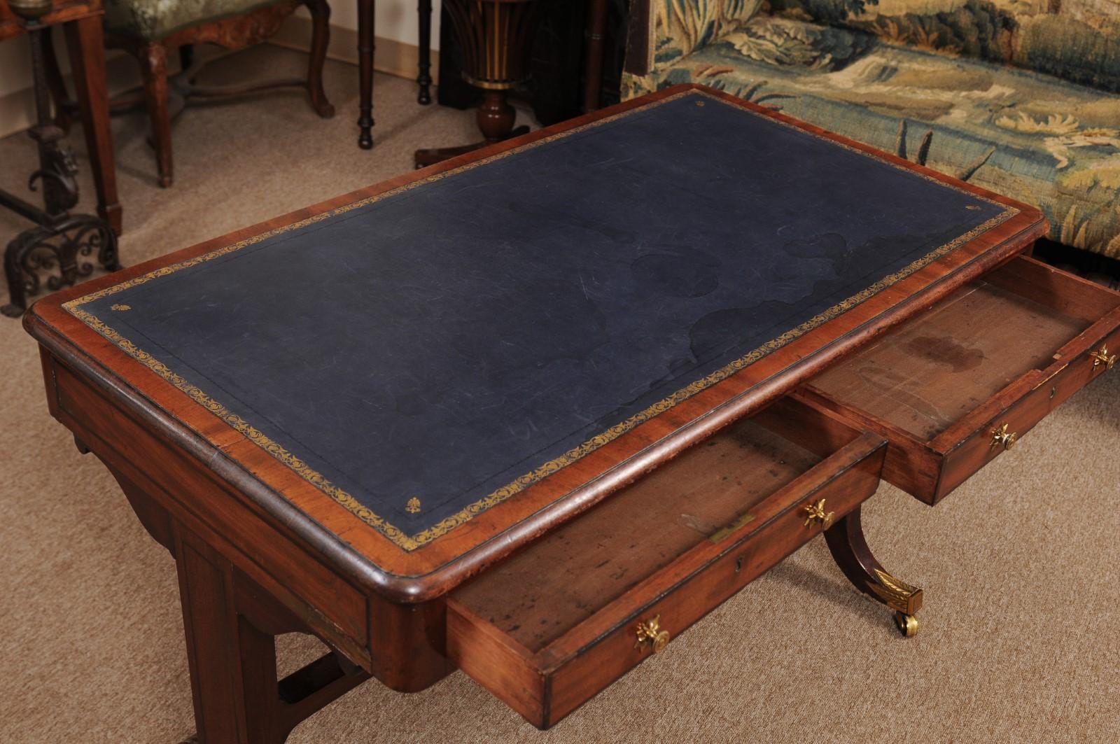 The Regency mahogany writing table with embossed blue leather top, inlay, two drawers with brass pulls, stretcher and splayed legs with brass castors. 

 