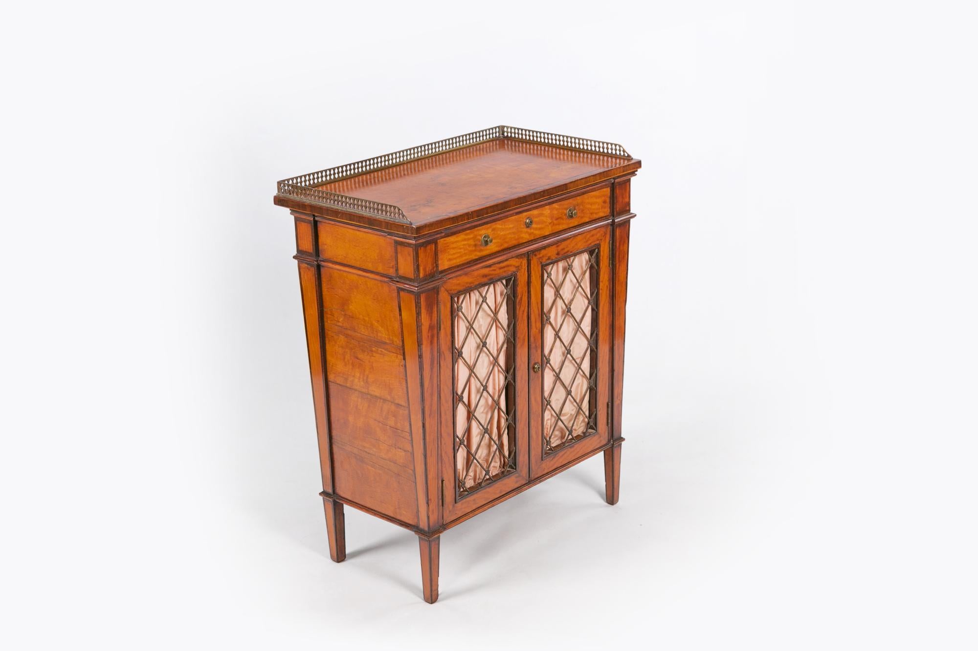 Early 19th century Regency miniature crossbanded cabinet, the moulded top with pierced brass gallery of rectangular form raised over single frieze drawer with brass ring pulls and escutcheon above two lined brass grill cupboard doors opening to