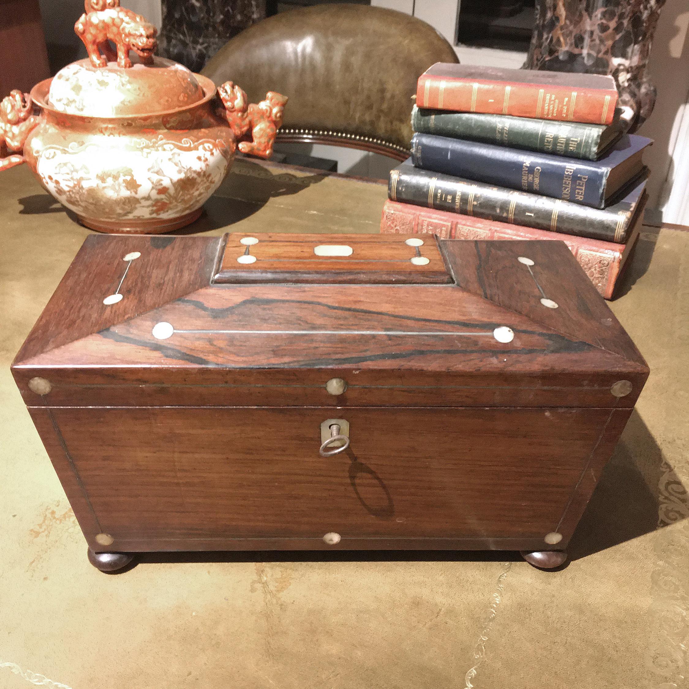 The body and hinged lid with mother of pearl and brass-line inlay. The fitted interior is lined with purple velvet. With a brass escutcheon and bun foot.
