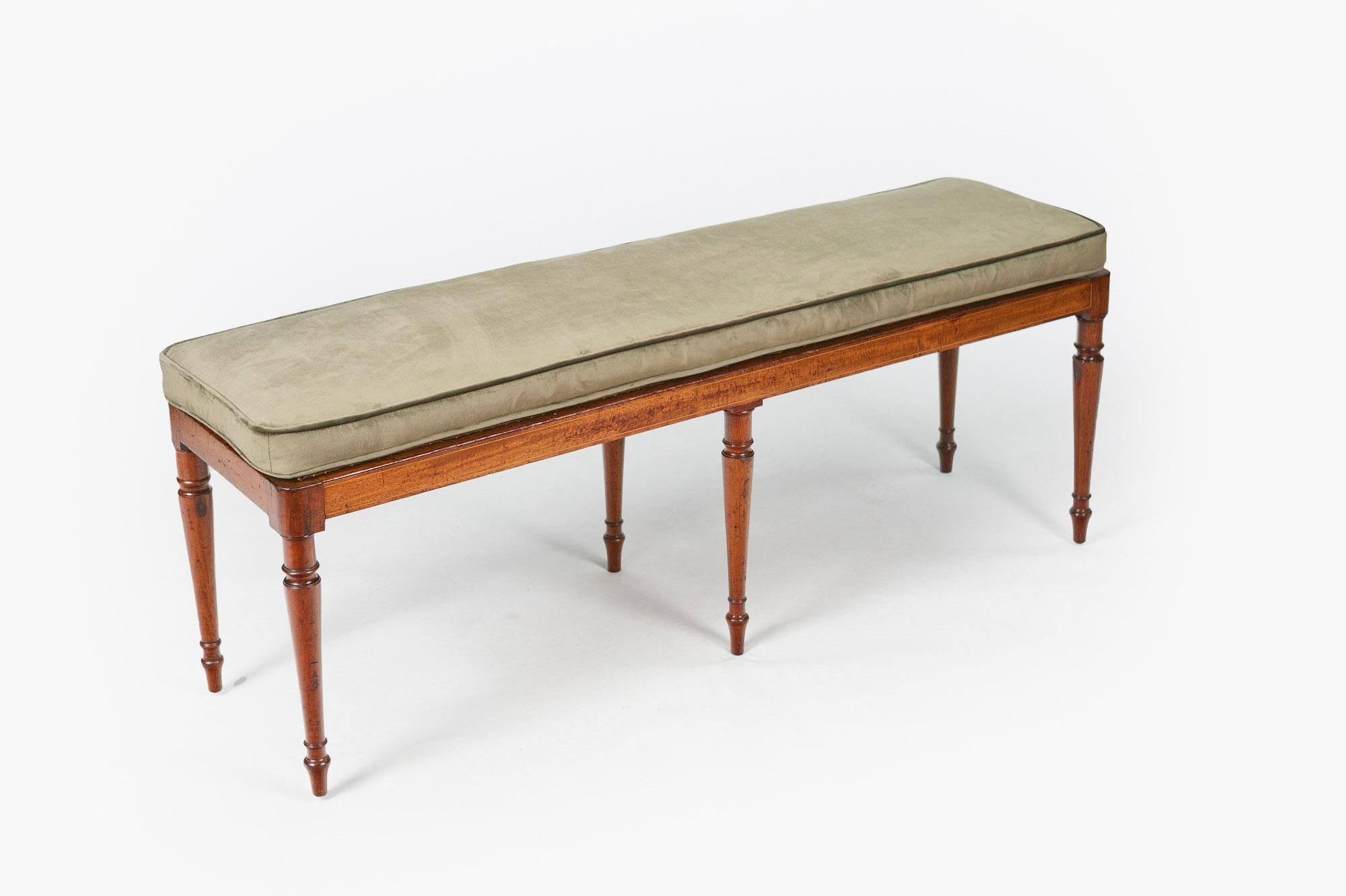 Early 19th century Regency neoclassical mahogany window seat, the moulded top with hand caned work seat supporting upholstered loose cushion raised over moulded frieze with satinwood line inlay supported on ring turned tapering leg terminating on