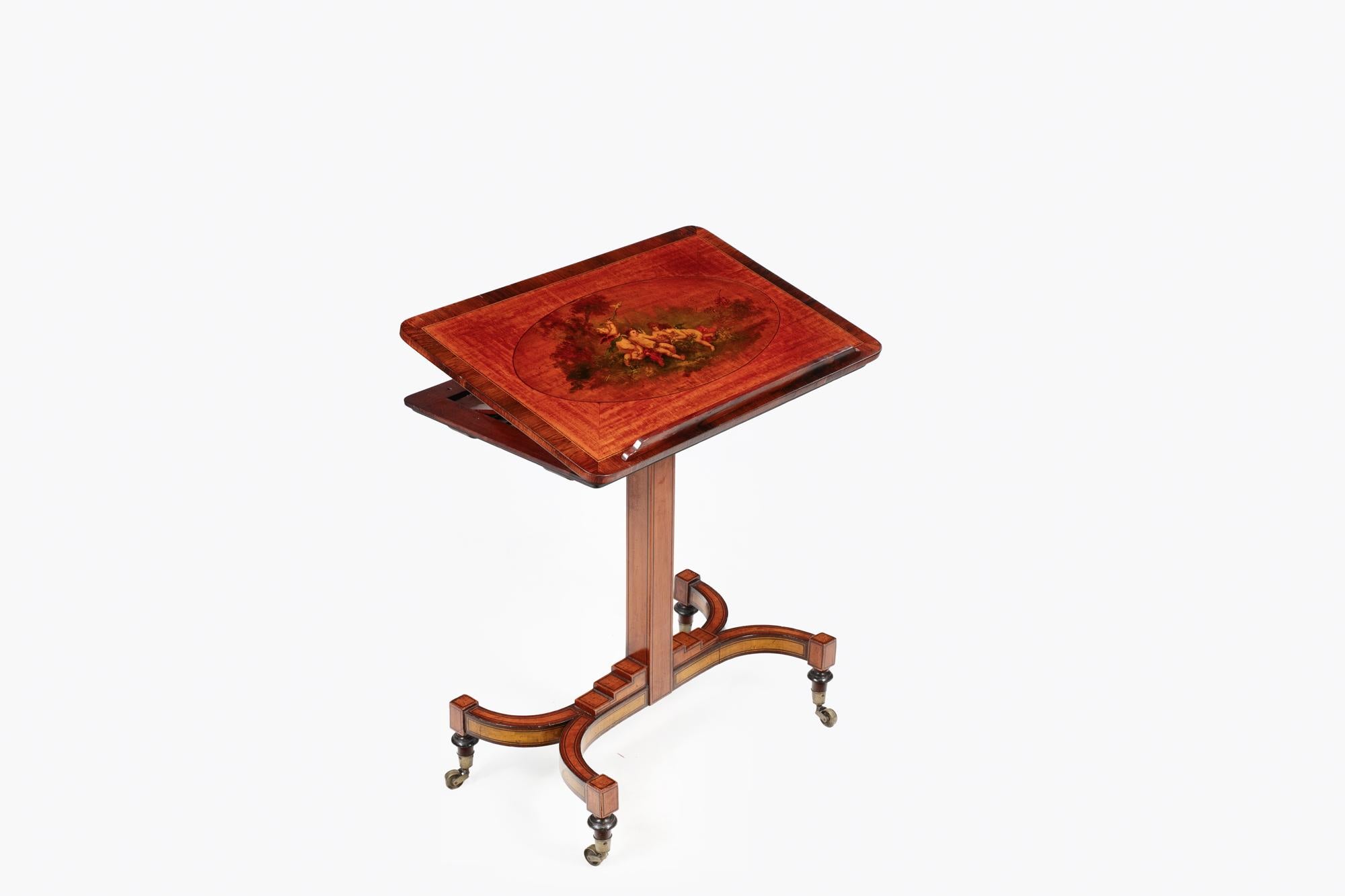 Early 19th Century Regency painted satinwood ladies’ writing table with box inlay throughout and an adjustable tilt-up top featuring rosewood cross banding and a painting depicting four cherubs. With adjustable height and securing pin. Supported by