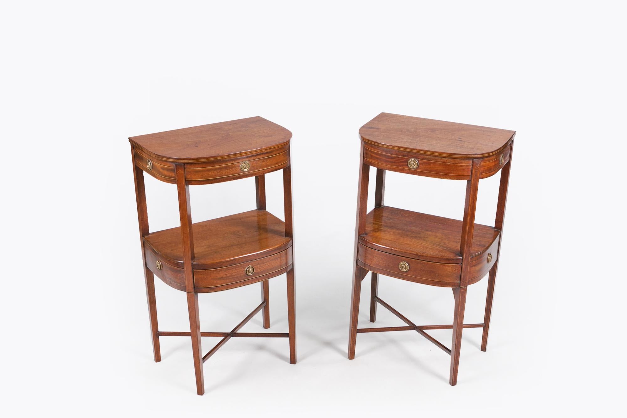 Early 19th century Regency pair of mahogany two tier bow front bedside lockers in the manner of George Hepplewhite, the moulded top with line inlaid satinwood and ebony edge raised over inlaid apron with central dummy drawer flanked with two side