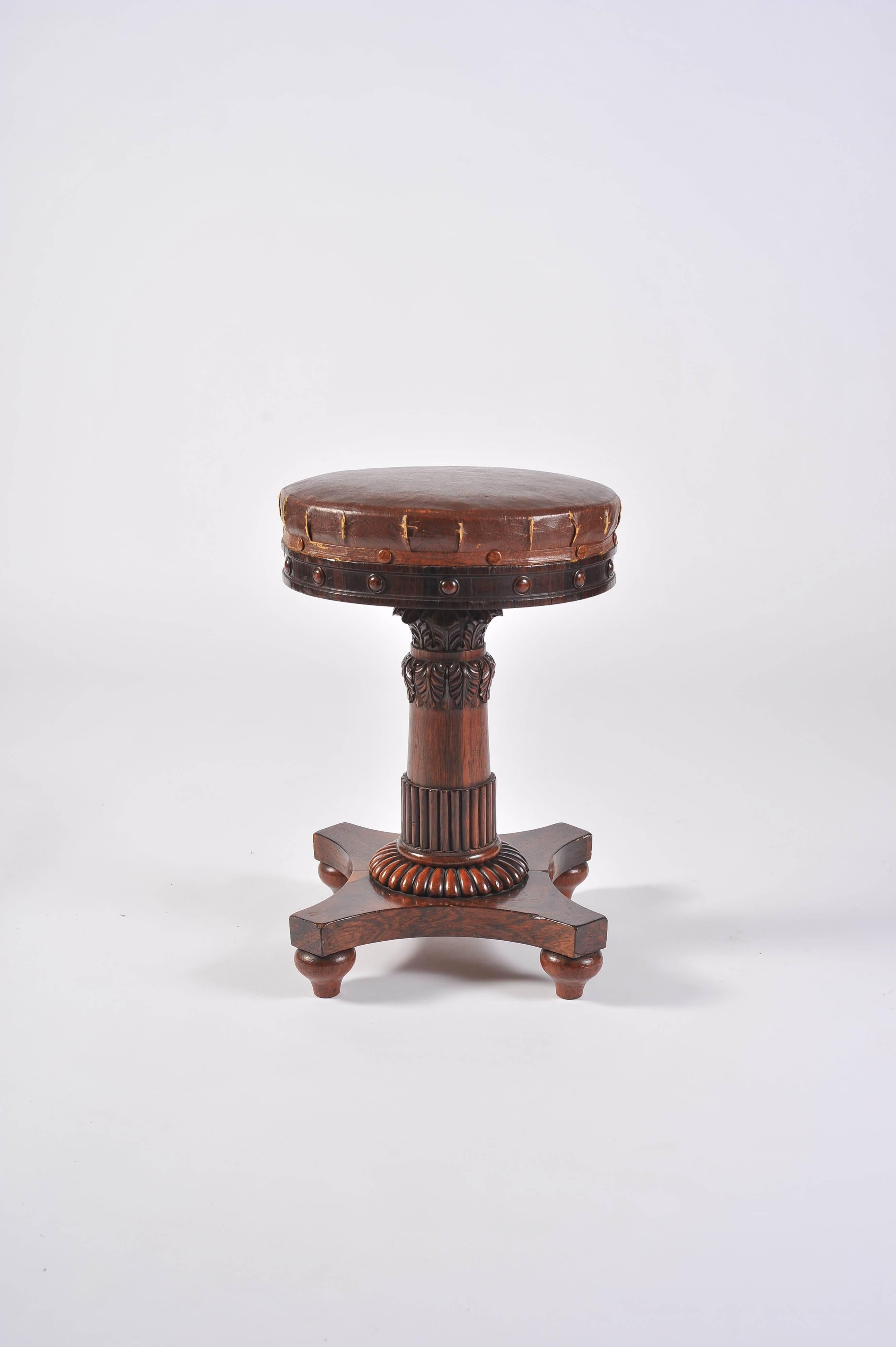 A wonderful Regency period rosewood music stool to designs by George Smith. The adjustable seat, with hand cut steel screw thread, on a turned rosewood stem with gilt metal collar and carved stylised acanthus leaf, reeding and gadrooning on a