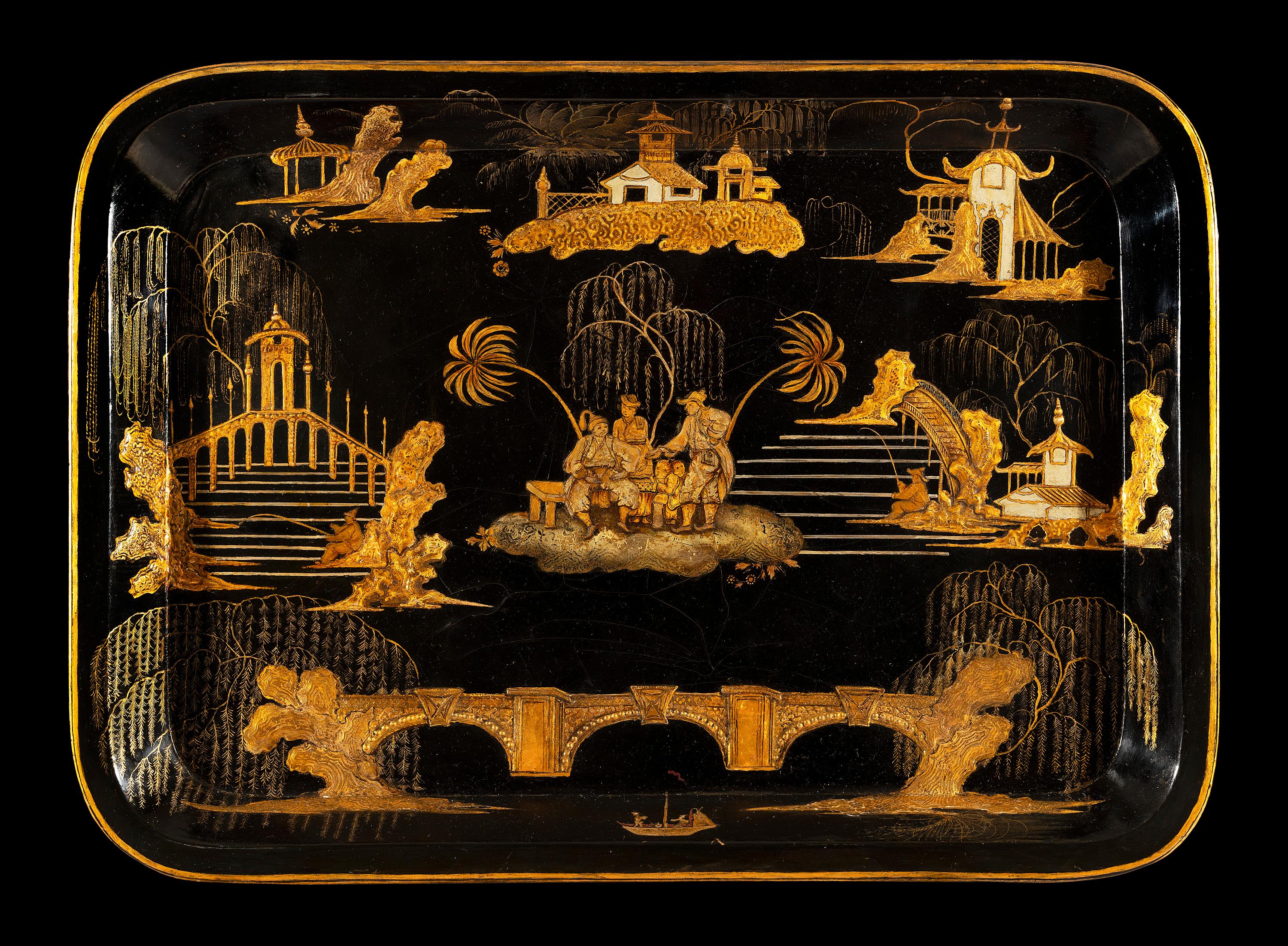 The grand-sized Regency black and gilt japanned tray is decorated with gilt chinoiserie and brightly coloured figures set in exotic landscapes. The tray has a modern glass top that we have had made to preserve the lacquer work. The x-frame stand is