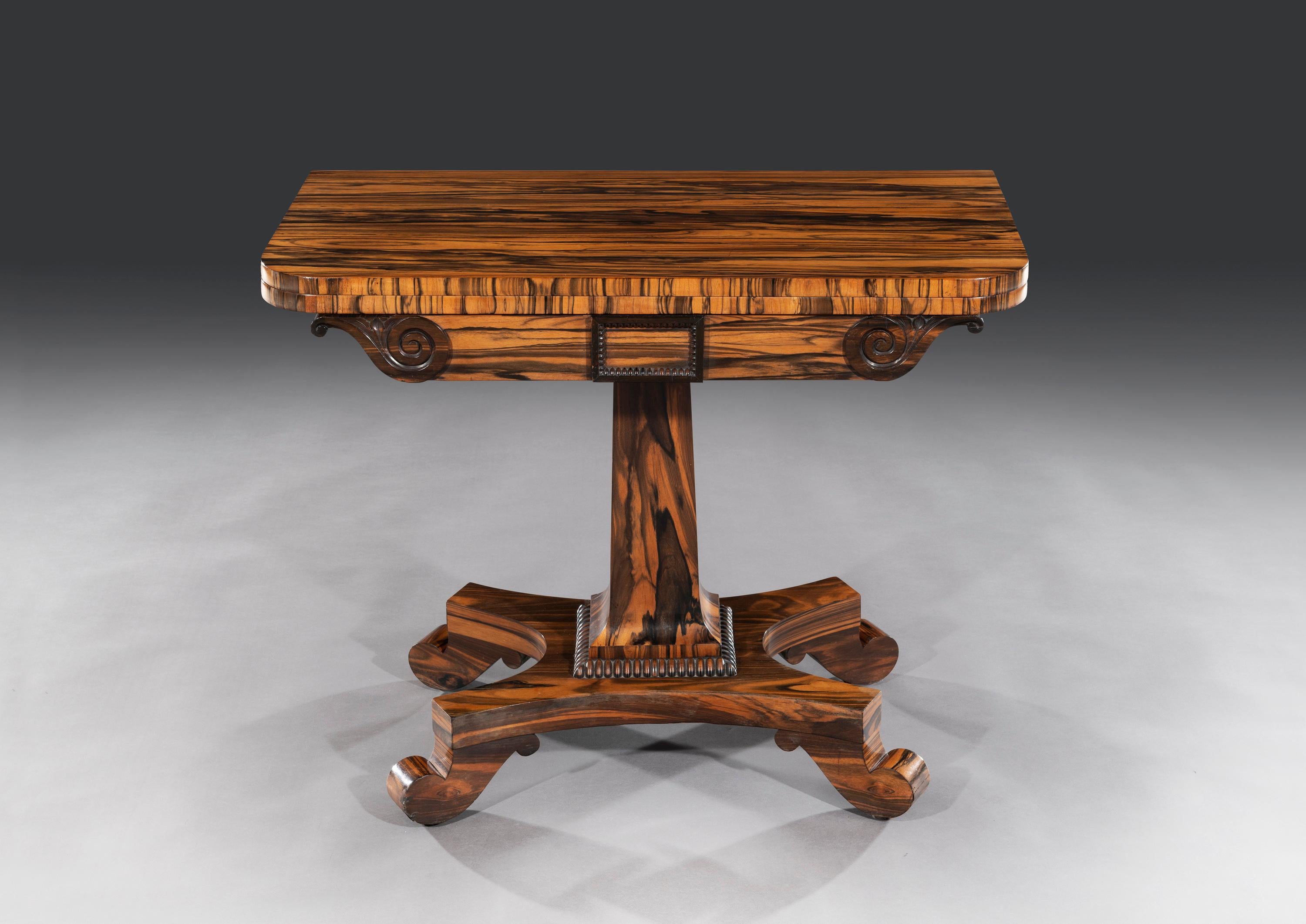 The card or gaming table is superbly figured, veneered and built in solid striped coromandel from Ceylon. The table is raised on a quadraphite platform base with scroll feet and concealed castors. The central shaped column with a carved beaded base