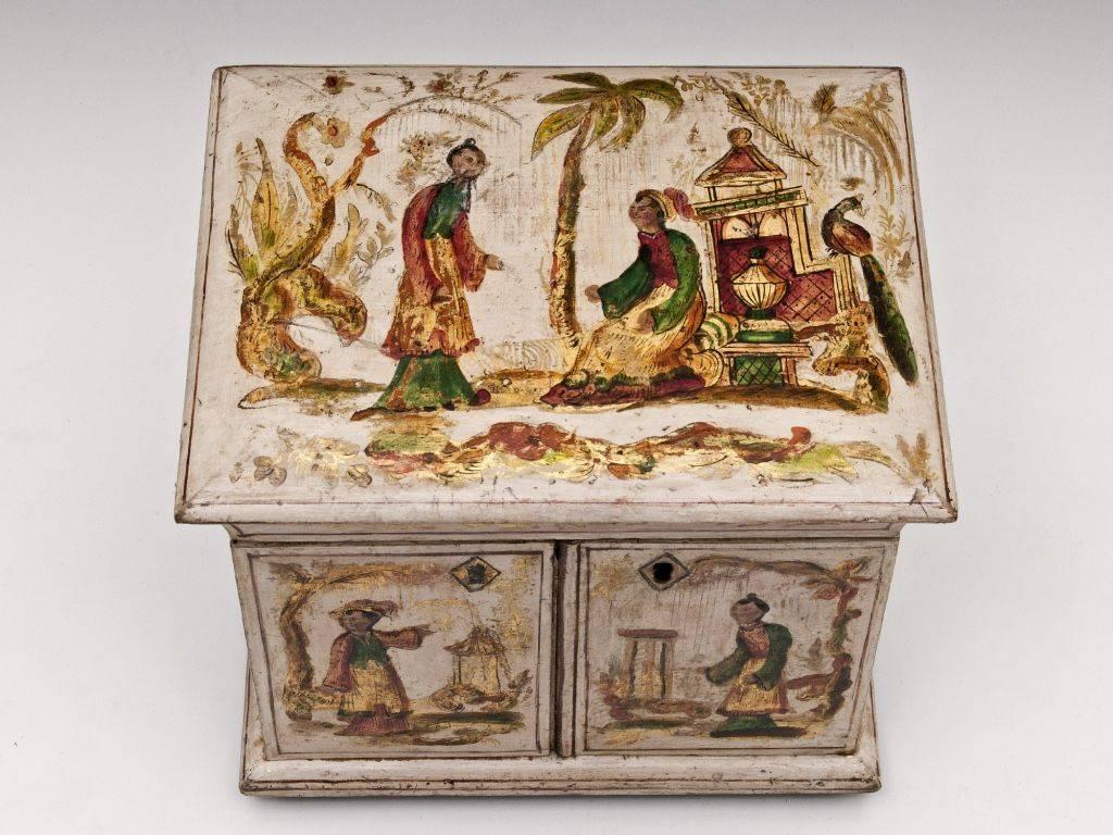 An exquisite little Regency cream and gilt japanned sewing table cabinet. Decorated on the top & front with gilt chinoiserie and brightly colored figures set in exotic landscapes. The sides, back and interior show further exotic scenes on a cream