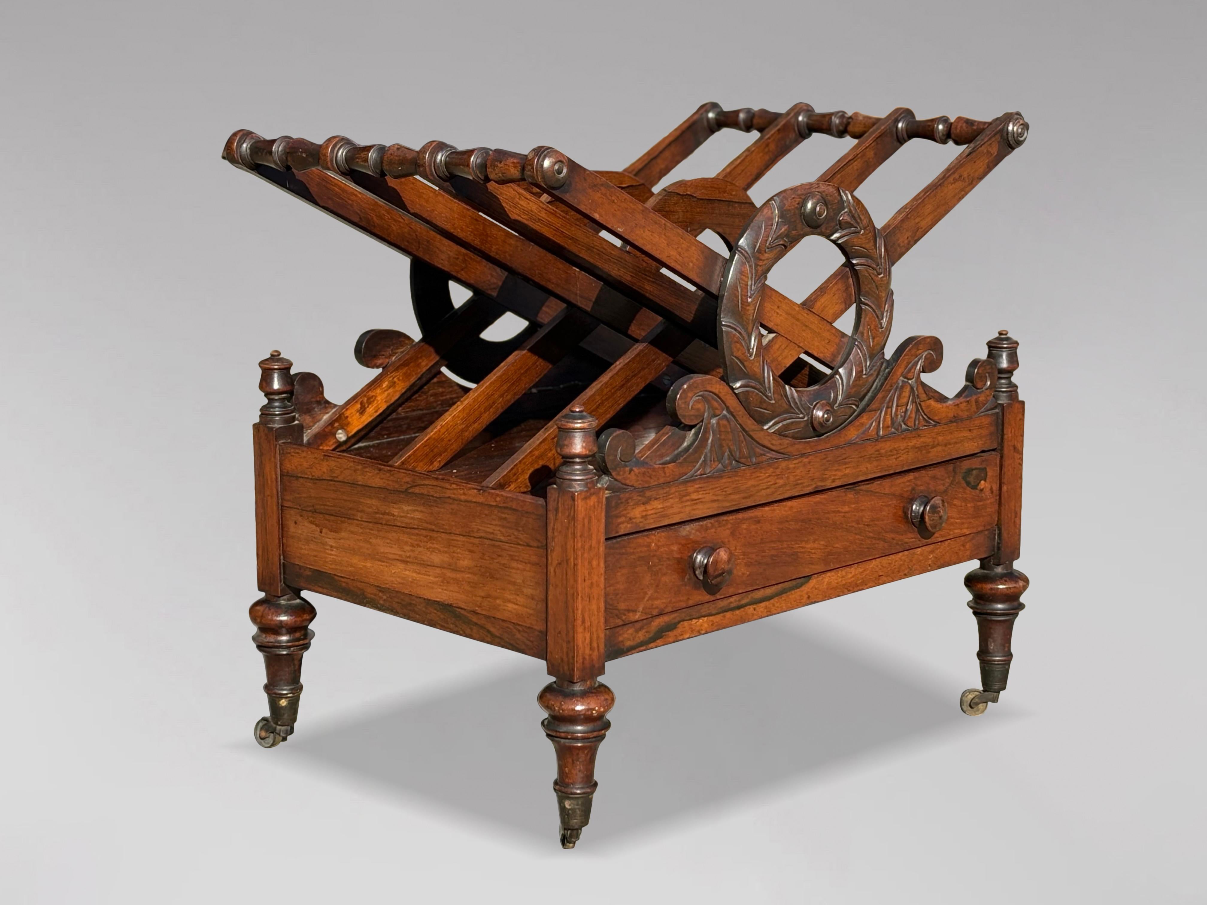 Un Canterbury in legno di palissandro dell'inizio del XIX secolo, utilizzato come porta riviste o giornali. Presenta un sorprendente piano a forma di X con un trio di scomparti di uguali dimensioni, ognuno dei quali è ornato da terminali torniti