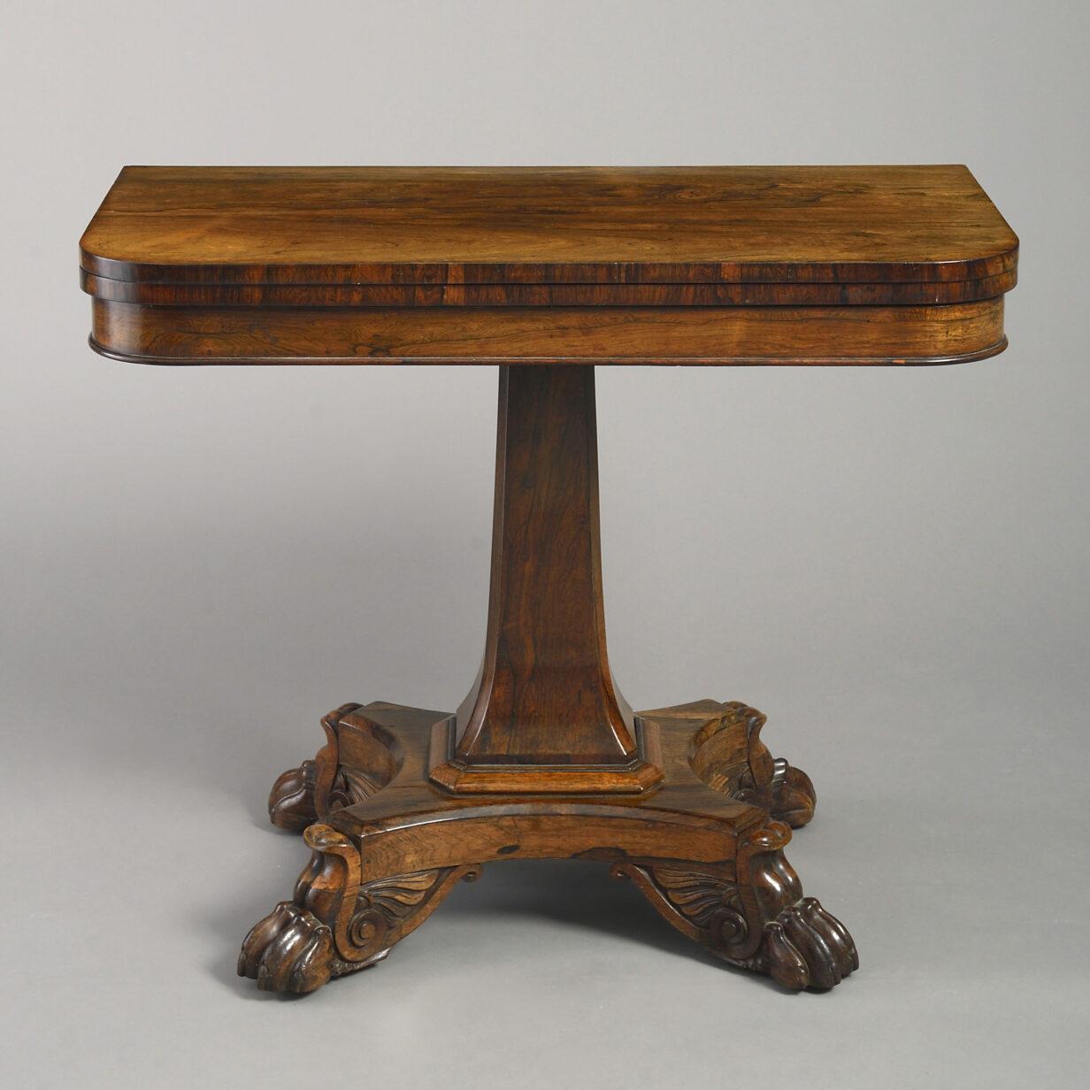 An early 19th century Regency period finely figured rosewood tea table, the D-shaped top swiveling to reveal a recess, set upon a square tapering stem, the concave plinth base terminating in richly carved winged lion paw feet.