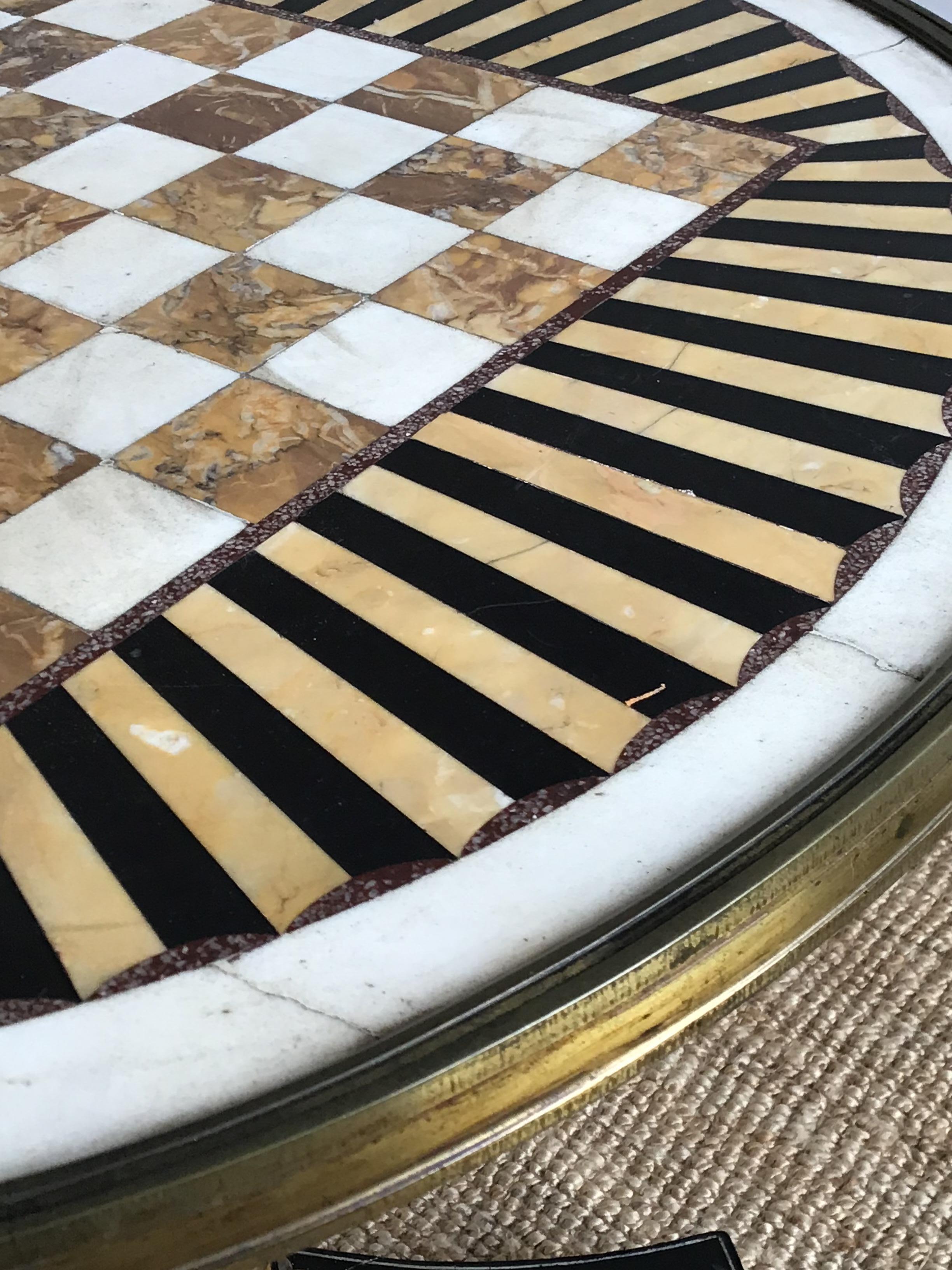 Early 19th century English Regency gilt metal bound games table with chess inset Sienna and Carrara marble with radiating bands of black and Sienna marble
The base ebonized and carved giltwood spiral twist fluted and lobed column to a triform
