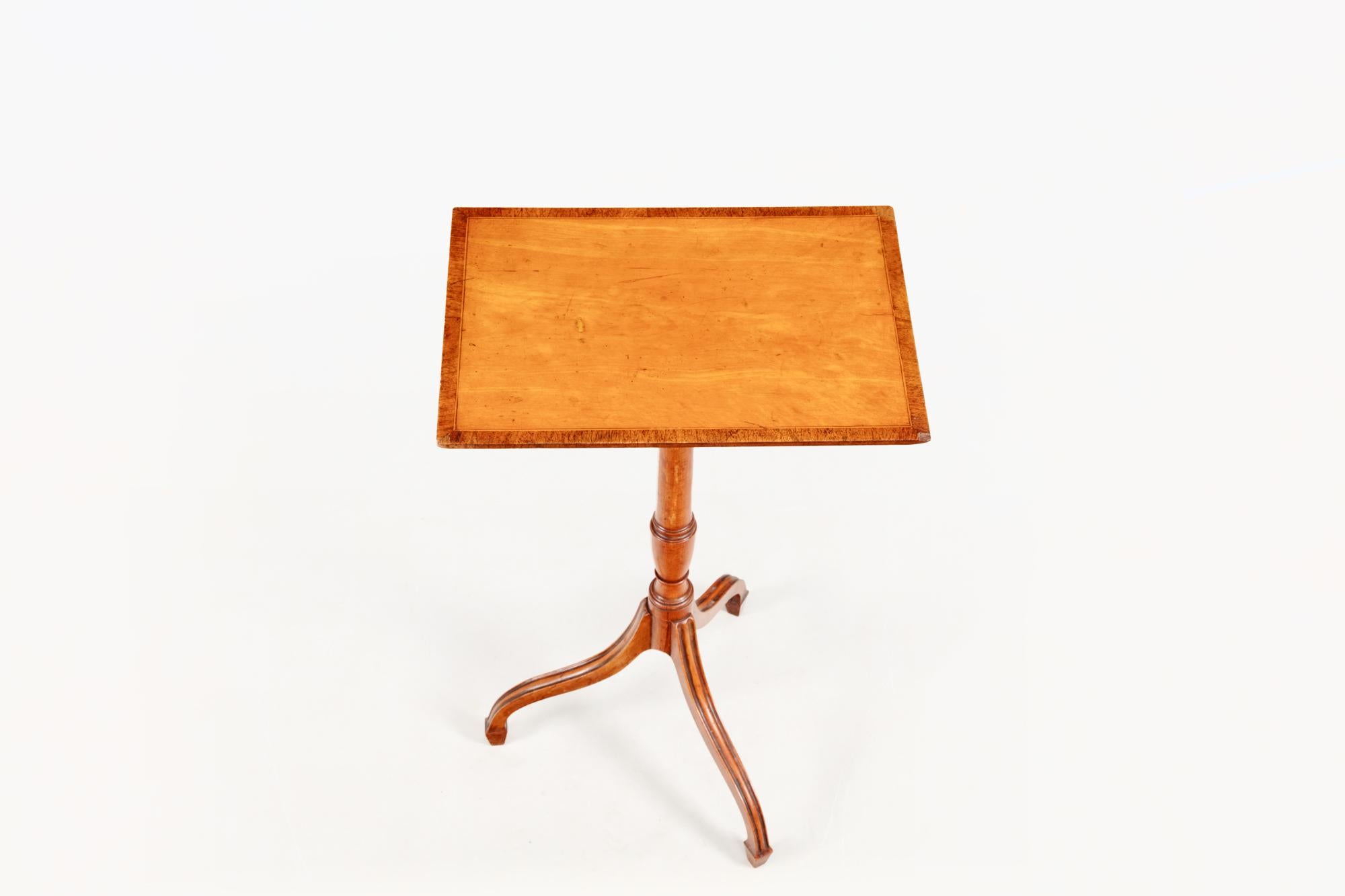 Early 19th century Regency tripod wine table. The rectangular satinwood and mahogany crossbanded top sits above a turned stem that splays out into three downswept tapering legs, terminating in simple spade feet.
