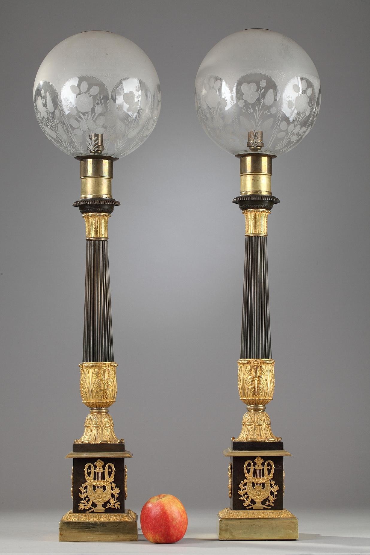 Pair of large Carcel lamps in bronze and glass. The fluted stem in patinated bronze is decorated with ormolu acanthus leaves. Each oil lamp is set on a small foliated base above a square plinth, decorated with crowns and lyres embellished with swans