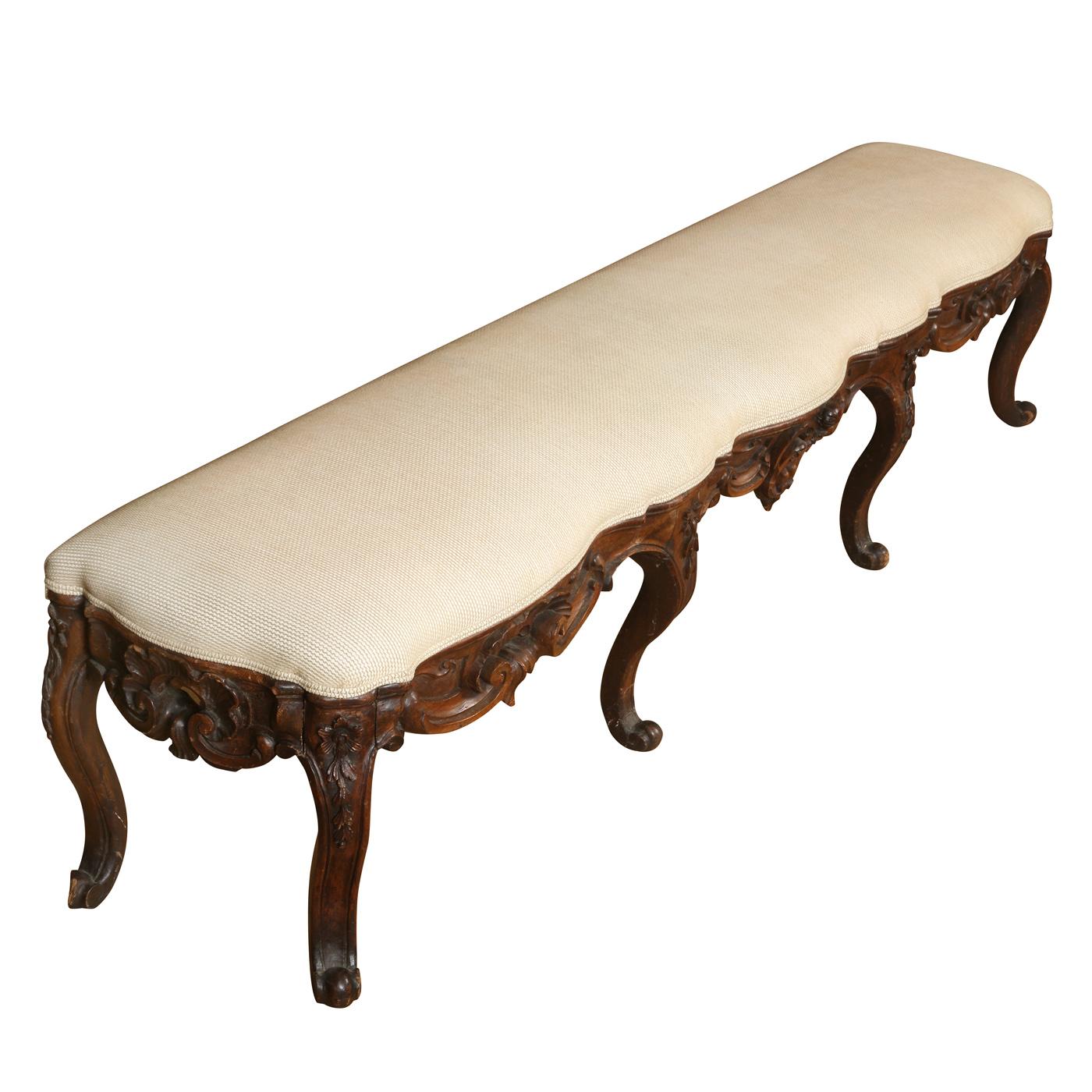 Early 19th Century rococo long walnut bench with neutral upholstery on carved cabriole legs.