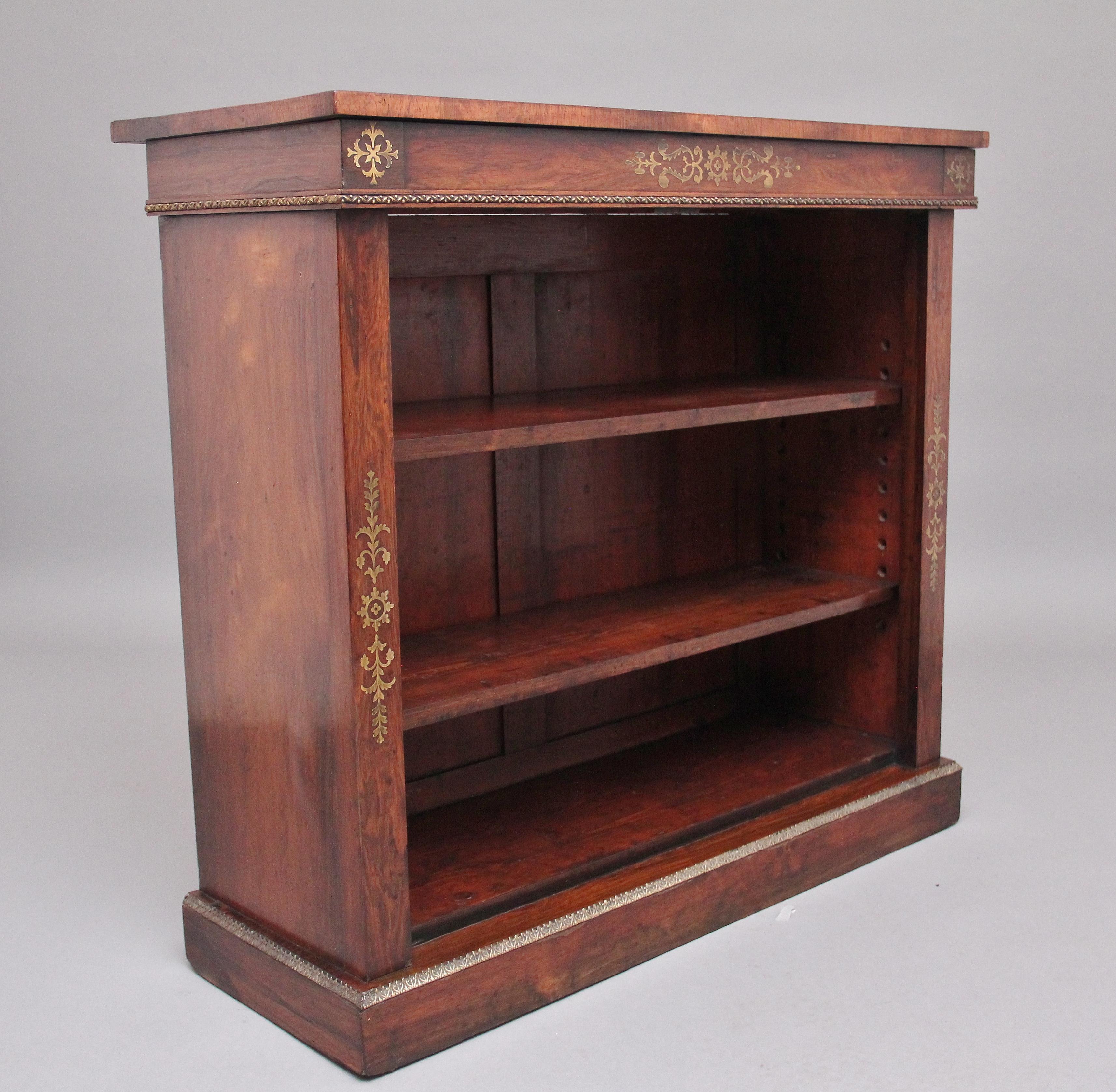 Early 19th century rosewood and brass inlaid open bookcase, having a nice figured top above the frieze decorated with brass inlay and ormolu beading at the bottom, the bookcase having two adjustable shelves flanked by columns with further brass