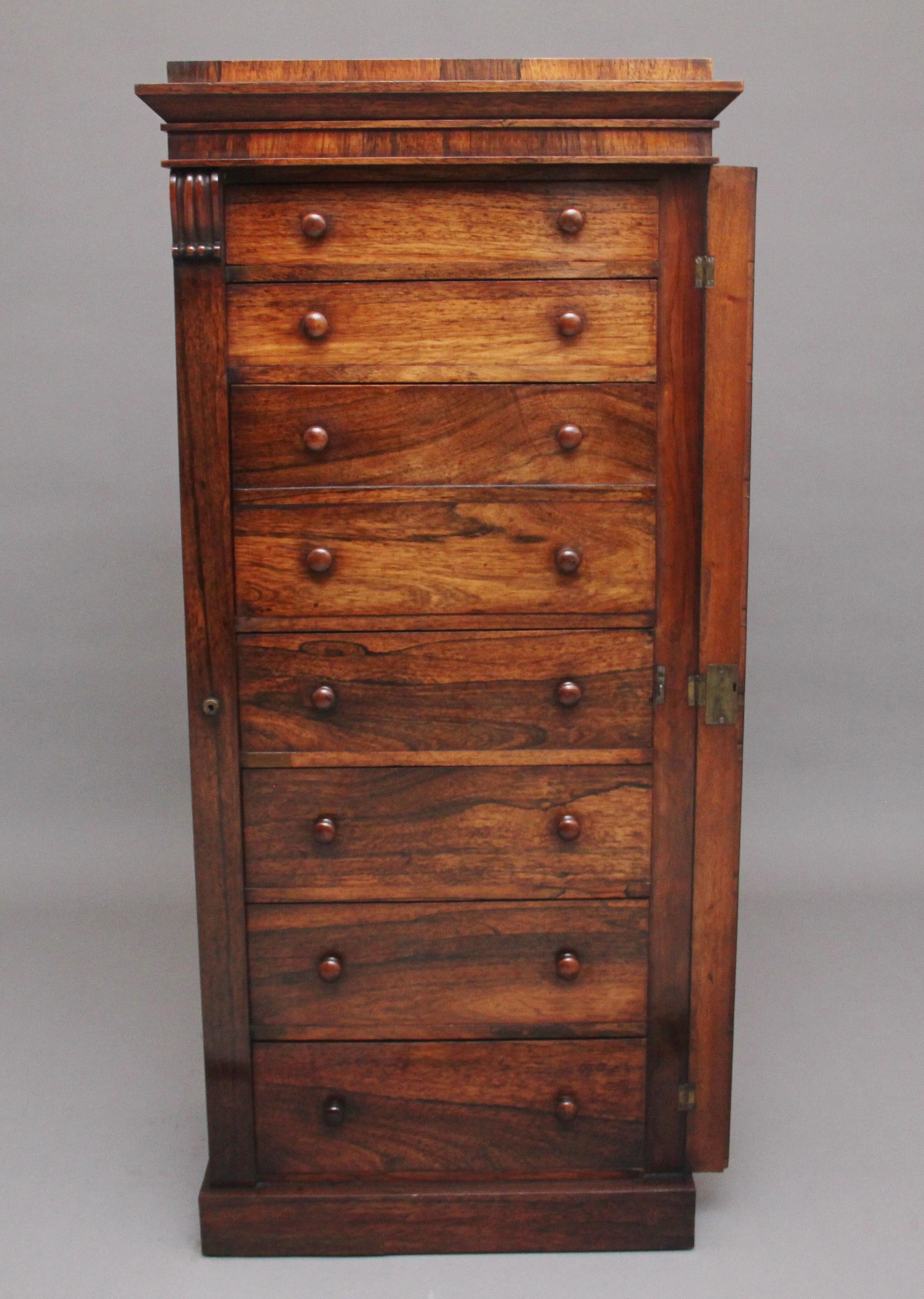 Early 19th century rosewood Wellington chest, having a nice figured top sitting above a shaped cornice, seven graduated drawers below with the original wooden turned knob handles, a secretaire drawer at the centre which pulls out and to reveal