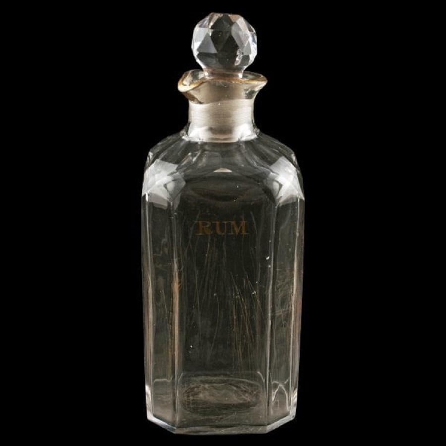 An early 19th century cut glass rum decanter.

The decanter has a square body with cut corners, facet cut shoulders, an shaped pouring lip with a gilded edge and a ground pontil mark.

Close to the top on one side of the decanter is the word RUM