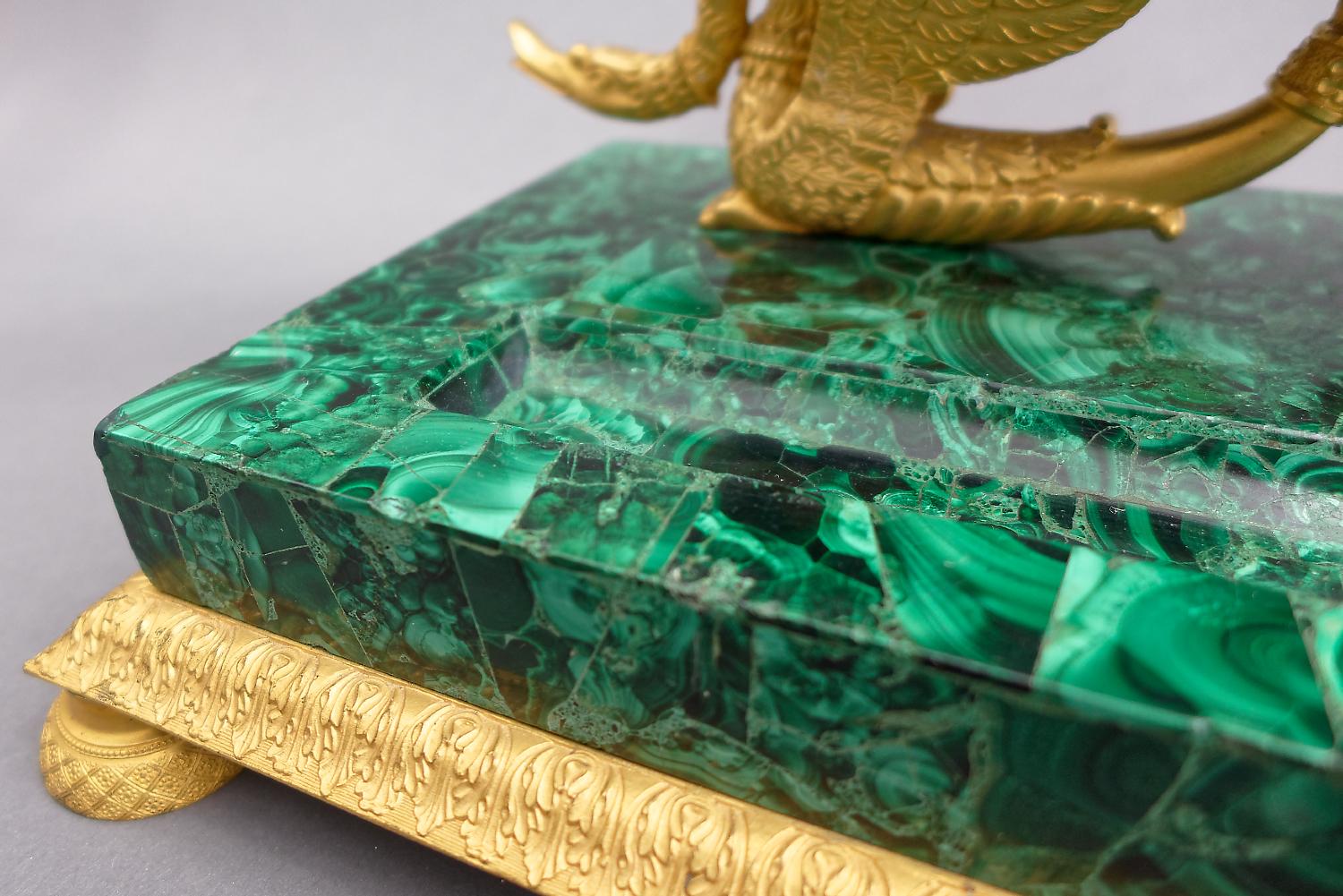 Très bel encrier russe en placage de malachite monté sur bronze doré du premier quart du XIXe siècle. De forme rectangulaire avec une bordure décorée de feuilles d'acanthe, sur des pieds ronds. Deux cygnes soutiennent les bouteilles en verre taillé.