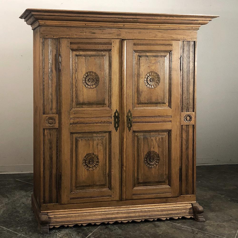 Early 19th century Rustic Dutch stripped oak armoire was handcrafted to last for centuries, and features large floral rosettes carved onto each of the four raised and recessed door panels. Original brass key guards and hinges add a nice touch, as