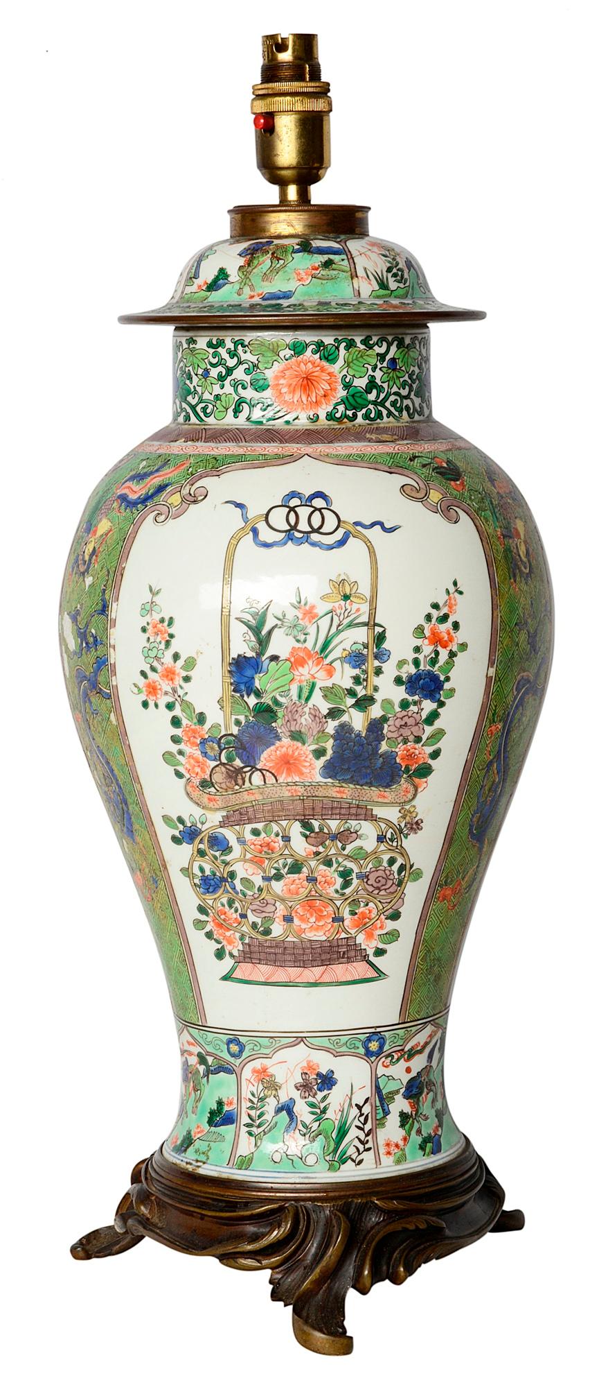 A very good quality early 19th century Samson porcelain lidded vase in the Chinese famille verte style. Having two inset painted panels each with a basket of wonderful exotic coloured flowers, a green ground with mythical dragons, birds and