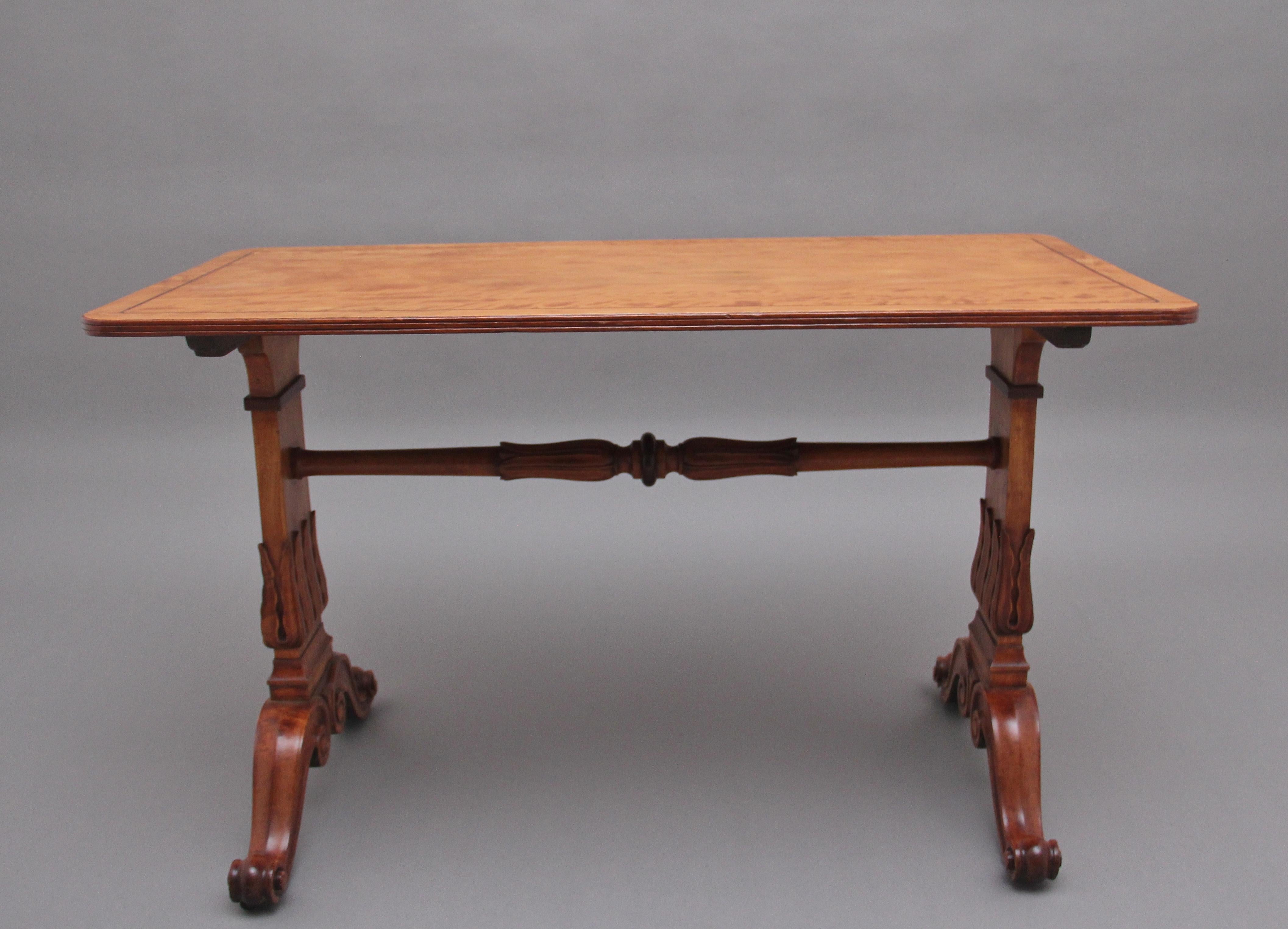 Early 19th Century satinwood sofa / occasional table, having a nice figured inlaid top with a reeded edge supported on decorative stiff leaf carved trestle ends united by a carved pole stretcher, on scrolling down swept supports. Circa 1840.
 