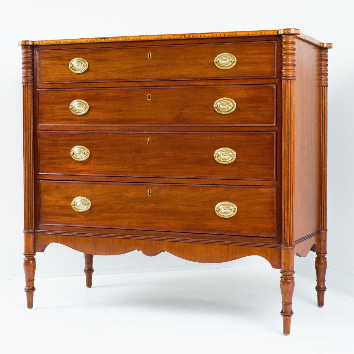 American Sheraton mahogany chest with graduated cock beaded drawers. The case top bears characteristic Seymour School lunette inlay on the edge of the single board mahogany top. The corners of the case are turreted with ring-turned dies over engaged