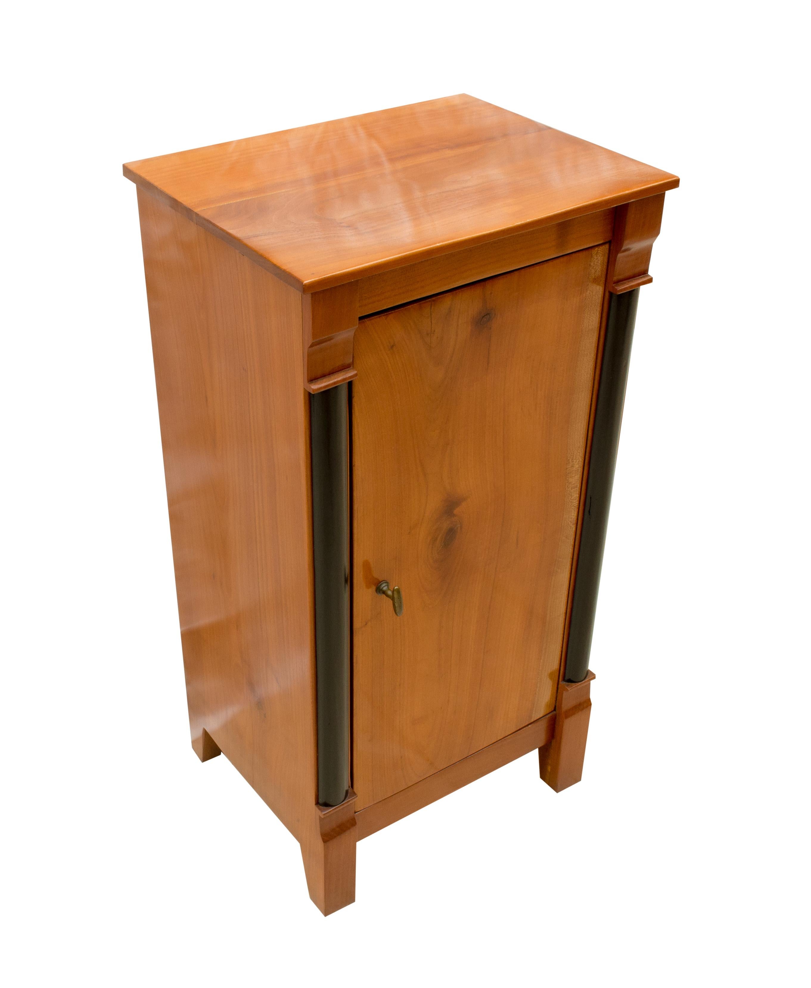 Original Biedermeier solid cherrywood nightstand or pillar cabinet from Germany. Back and shelf is made of pinewood as usual. The opening handle is made of brass. The furniture is in a very good, restored condition.