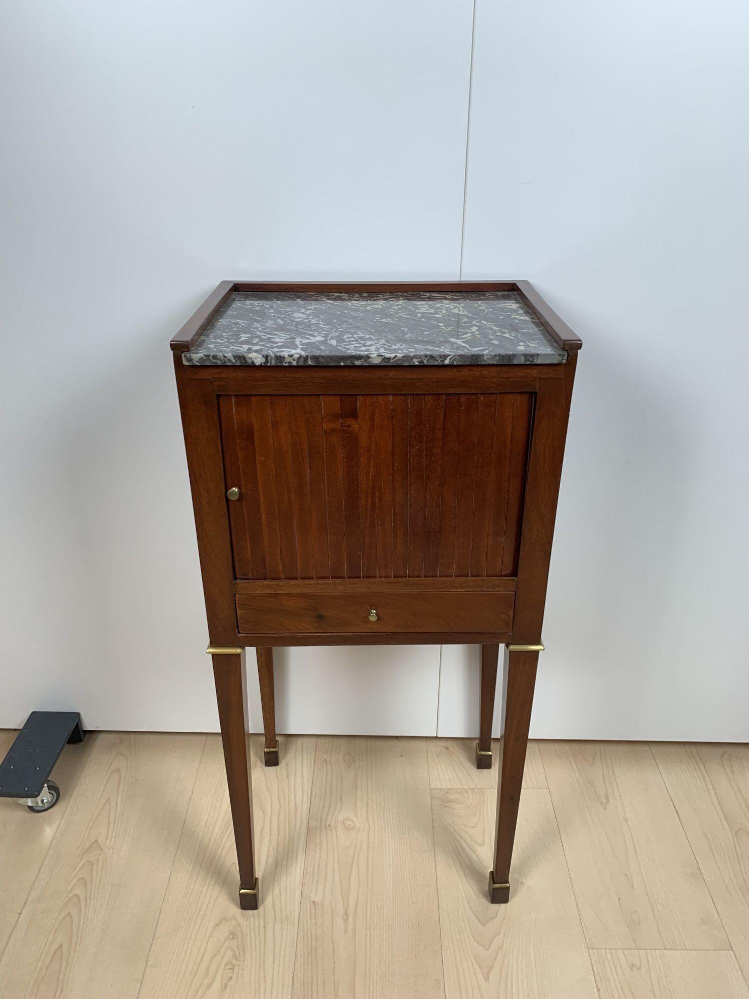 Beautiful Biedermeier / french Restoration period Nightstand, or small furniture from France circa 1820.

Mahogany veneered and solid. Conical square legs with two brass rings per leg. 1 roller lock and 1 drawer. Veneered on 4 sides and therefore