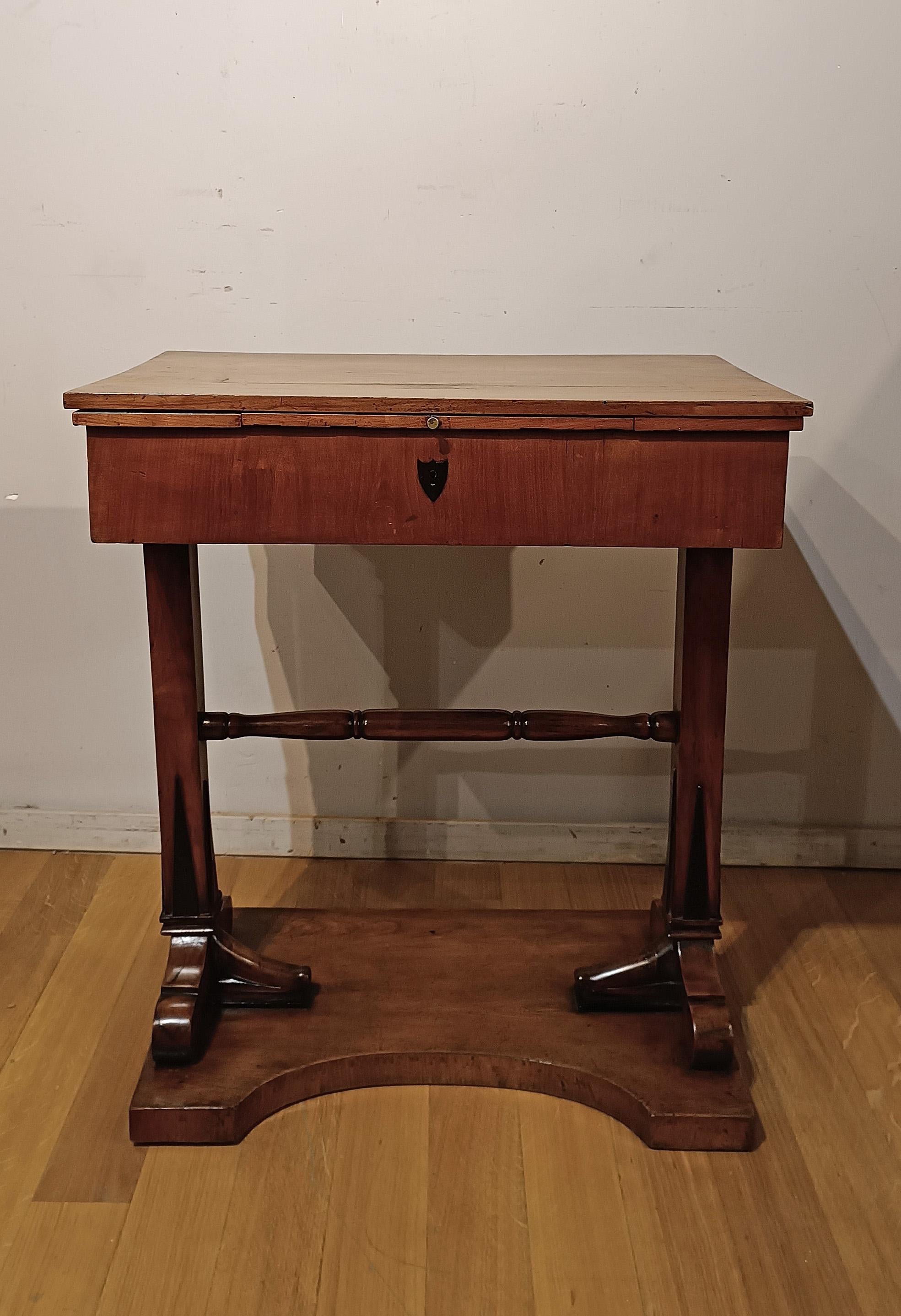 This splendid and refined cherry working table, of Tuscan manufacture from the early 19th century, is a unique piece that can also be used as a small desk. Its ancient function was that of a work table, as demonstrated by the presence of internal