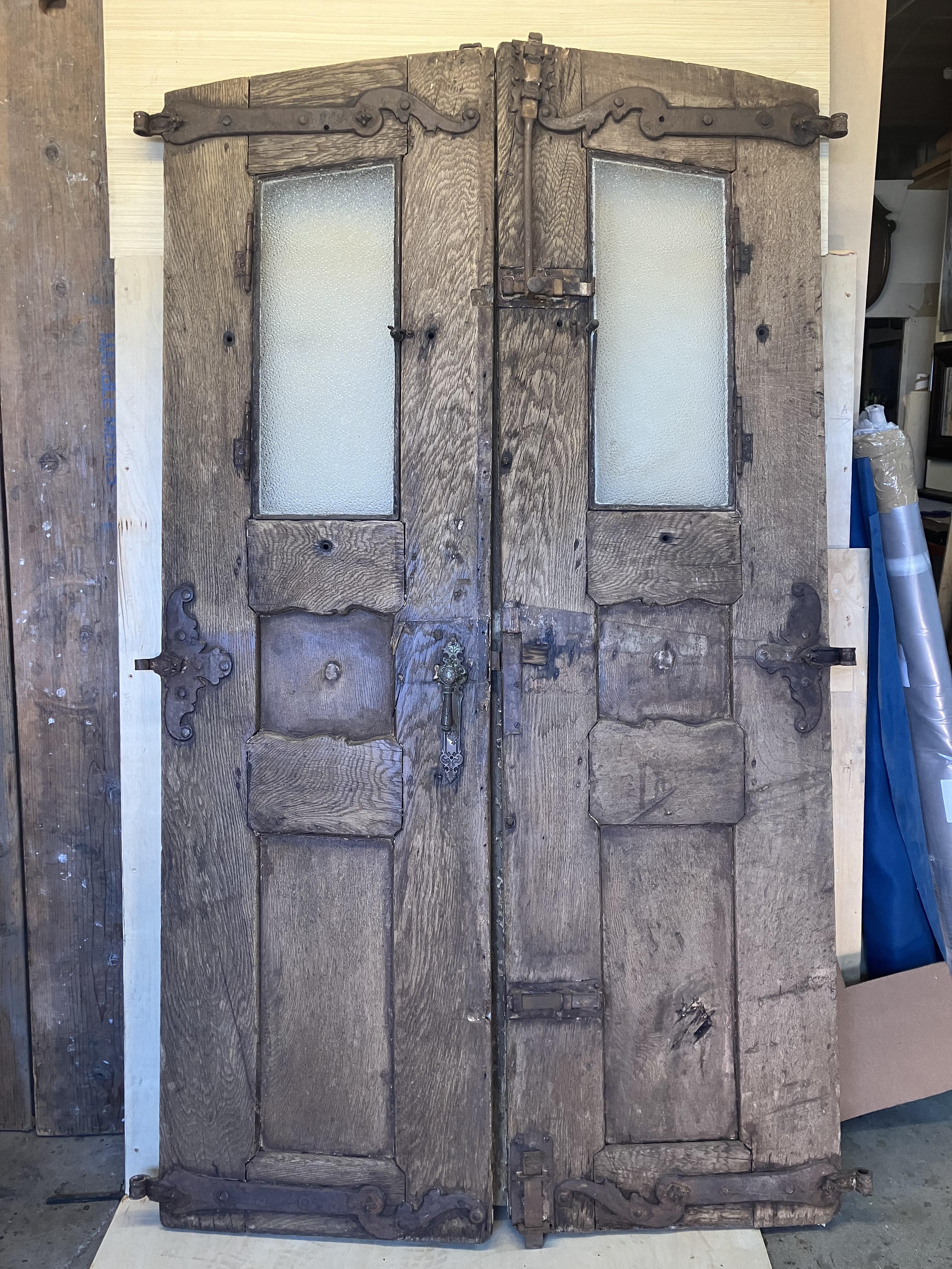 Pair of stunning srtipped Spanish American doors with wrought iron
Hand made with thicks planks of aged old oak, were designed to defy aging with bold molded detail
The doors have Iron framed glazed frosted glass used as openings to see who may want