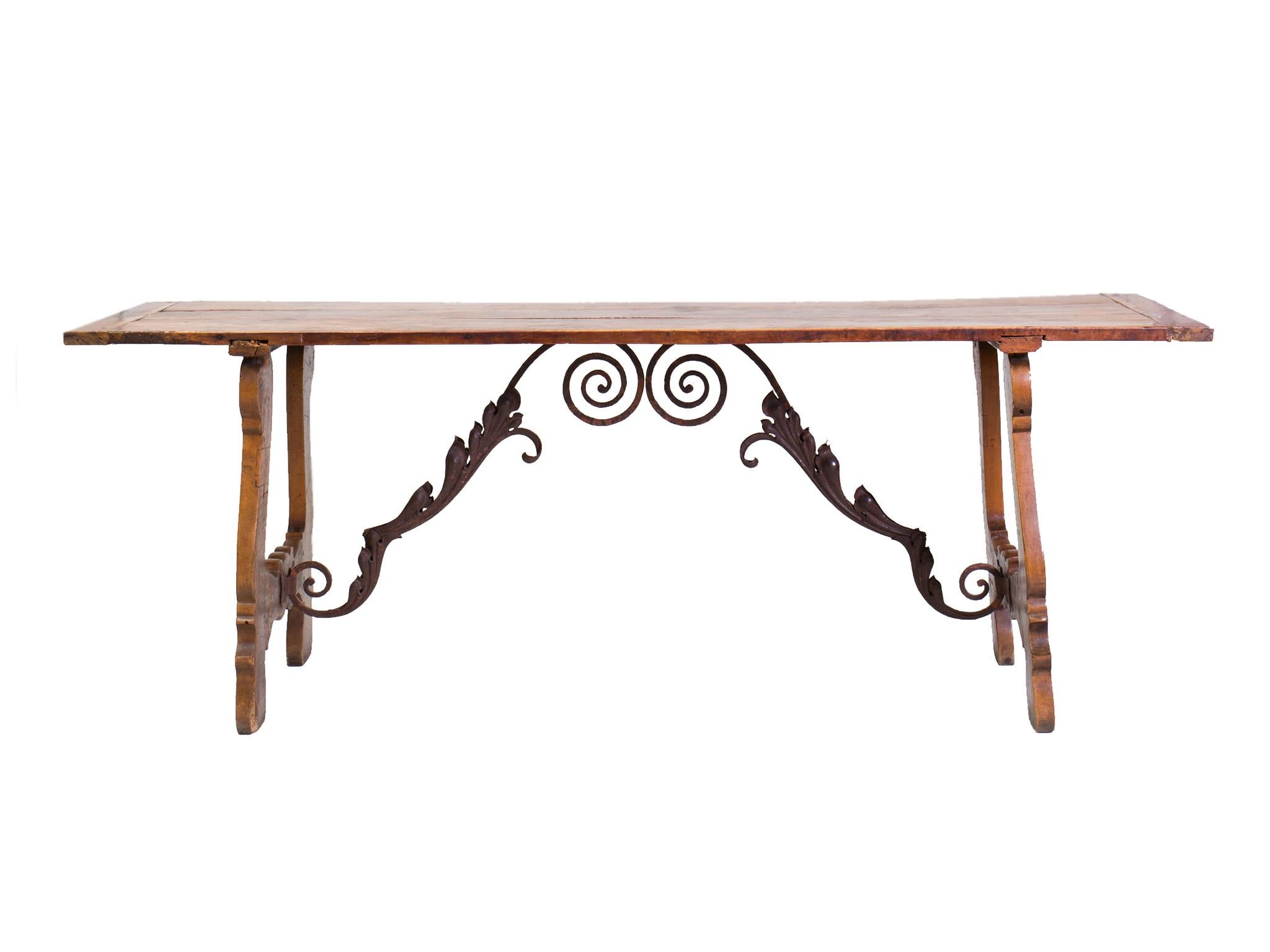 This 19th century dining table was designed and crafted in the Spanish Baroque style. It is comprised of elmwood. The surface has aged beautifully here, accruing a weathered patina that gives the table a historical presence. The legs and tabletop
