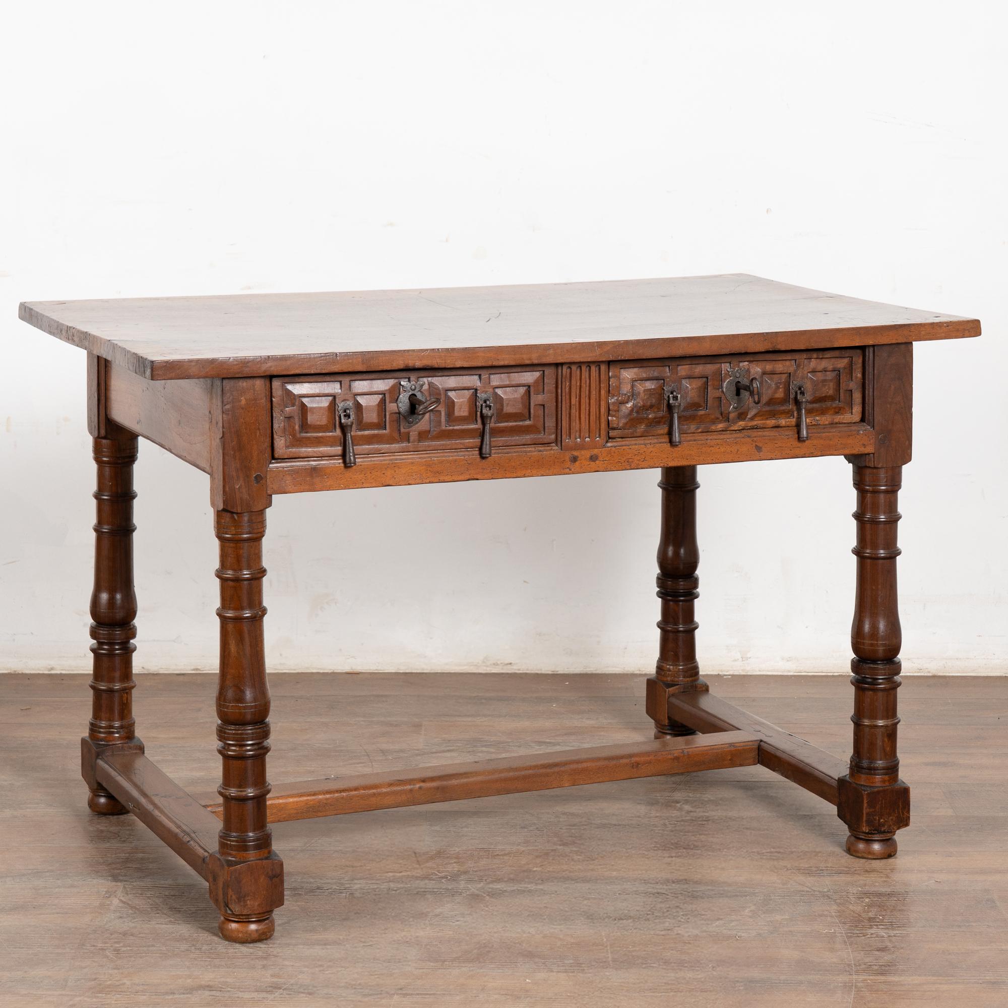 Early 19th-century Spanish chestnut console table with carved drawers, turned legs, and stretcher base. Two drawers, each fitted with two drop pulls and an old skeleton key (locks non-functioning).
Restored, strong, and stable, ideal as a writing