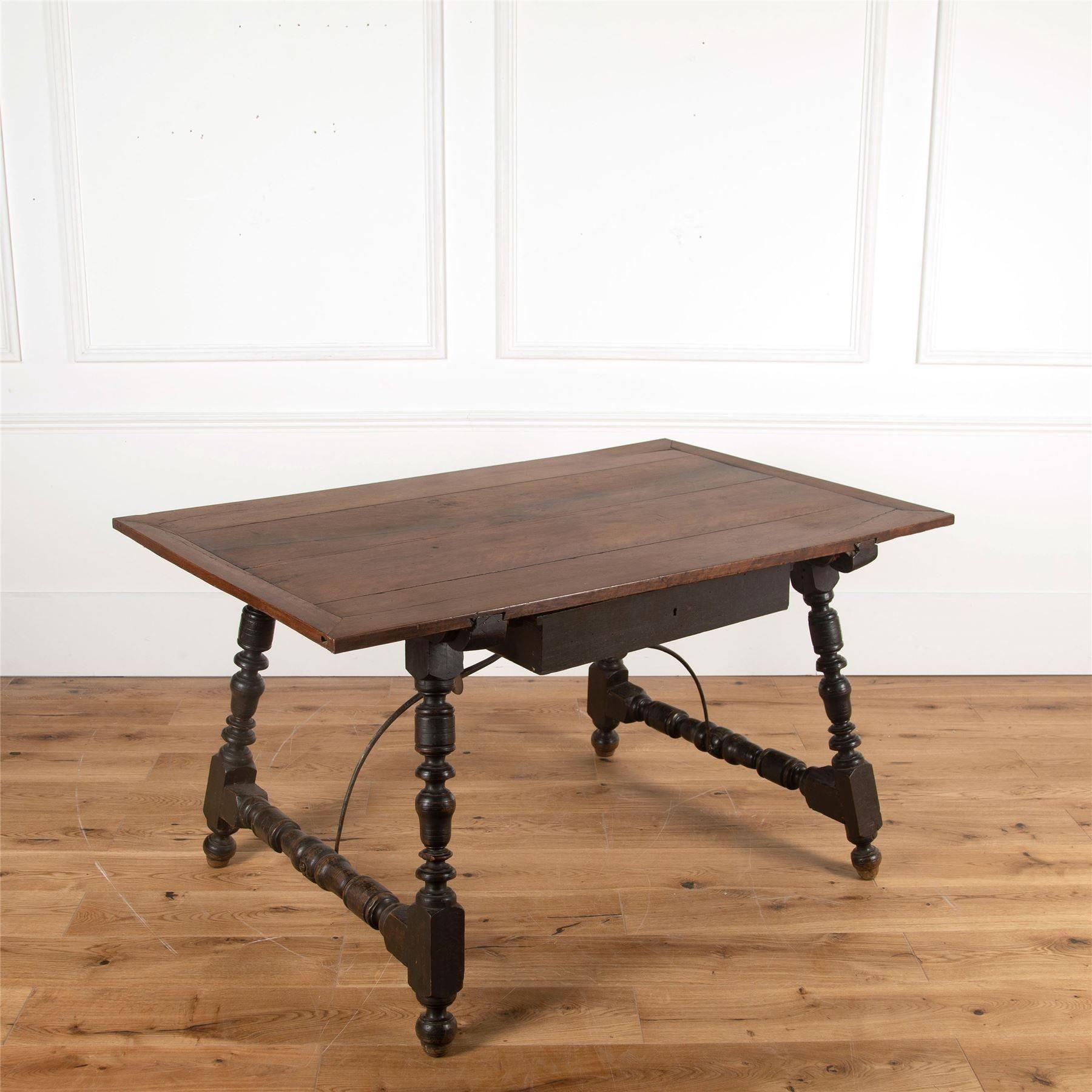 A late 18th / early 19th Century Spanish walnut table with hand-forged iron stretchers. Featuring richly carved legs and a central drawer.