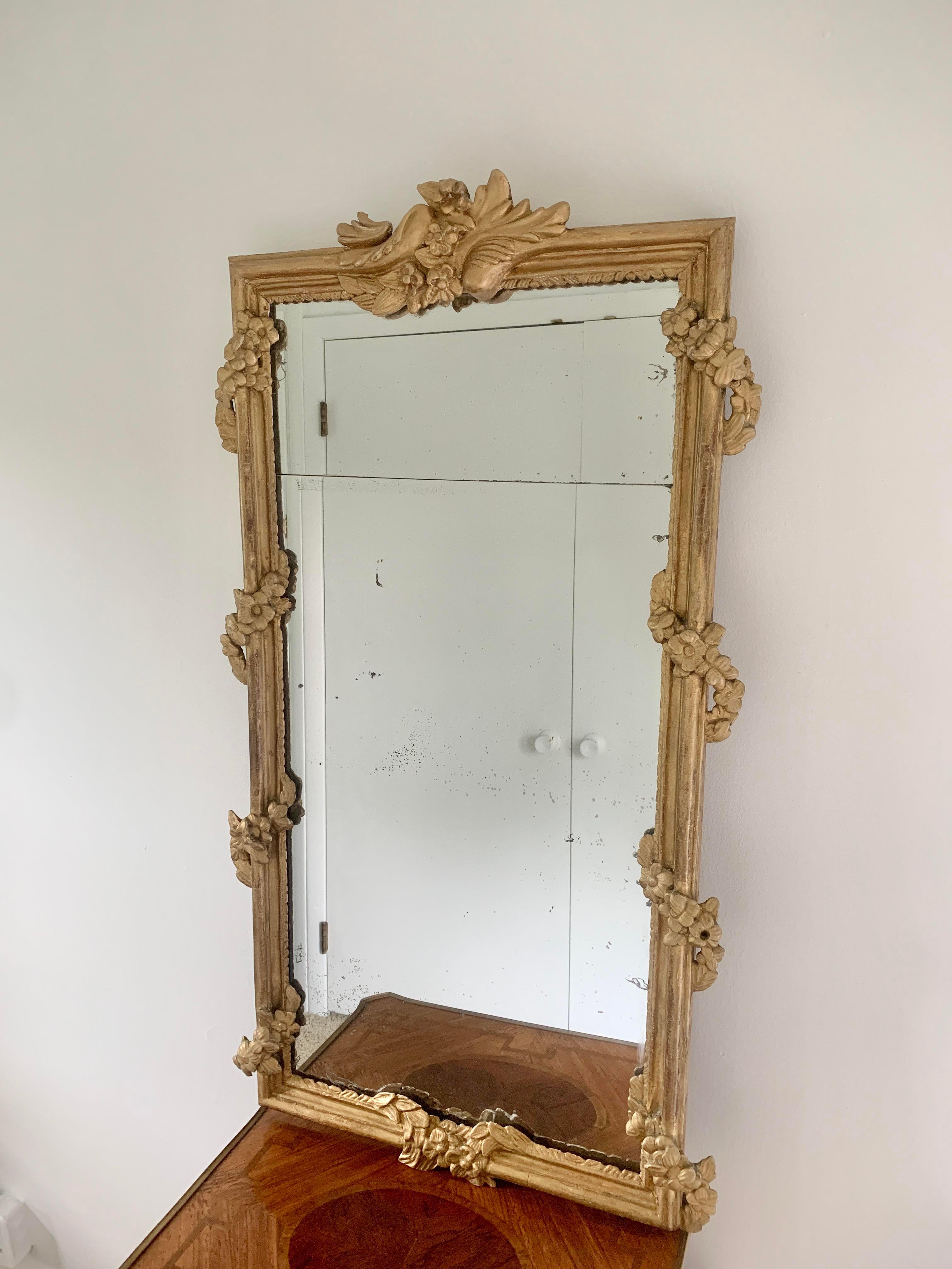 A beautiful early 19th century French split plate mirror set in a gilt wood frame. The frame is adorned with a gilt wood floral garland. The mirror is in good condition with age appropriate wear. 

France, Early 19th Century

Measures: 23.5ʺW × 3ʺD