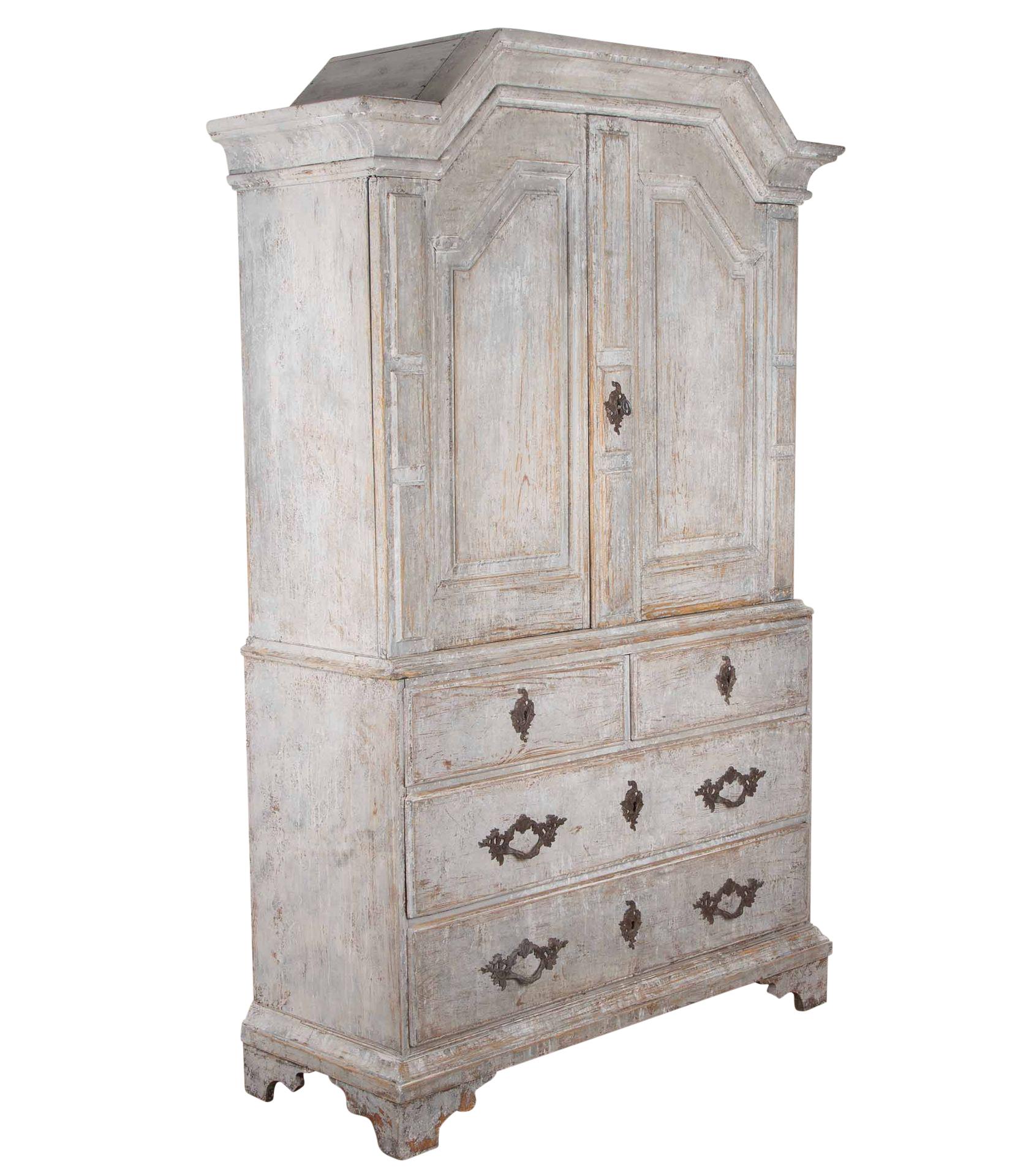 Early 19th Century Swedish cabinet.
With deep carved pediment, below two doors with decorative carvings to the doors and edges, opening to useful storage. Further below two shorter and two longer drawers.
Re-painted in soft grey. With good smaller