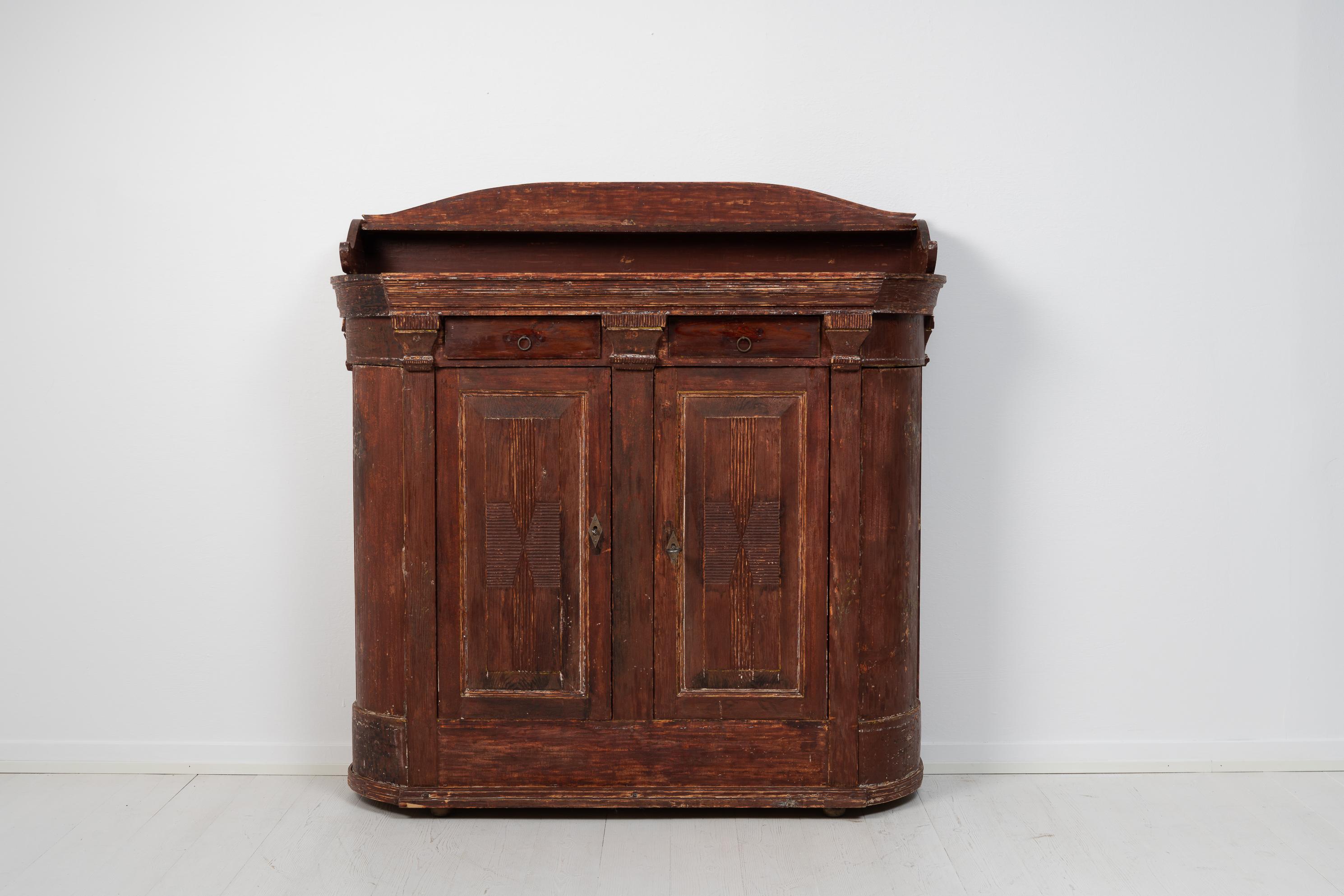 Country house sideboard with a curved front from northern Sweden. The sideboard is from the 1820 to 1830s and is made in painted pine. It has two doors and rounded corners as well as a hand carved decor. It also has two drawers as well as shelves
